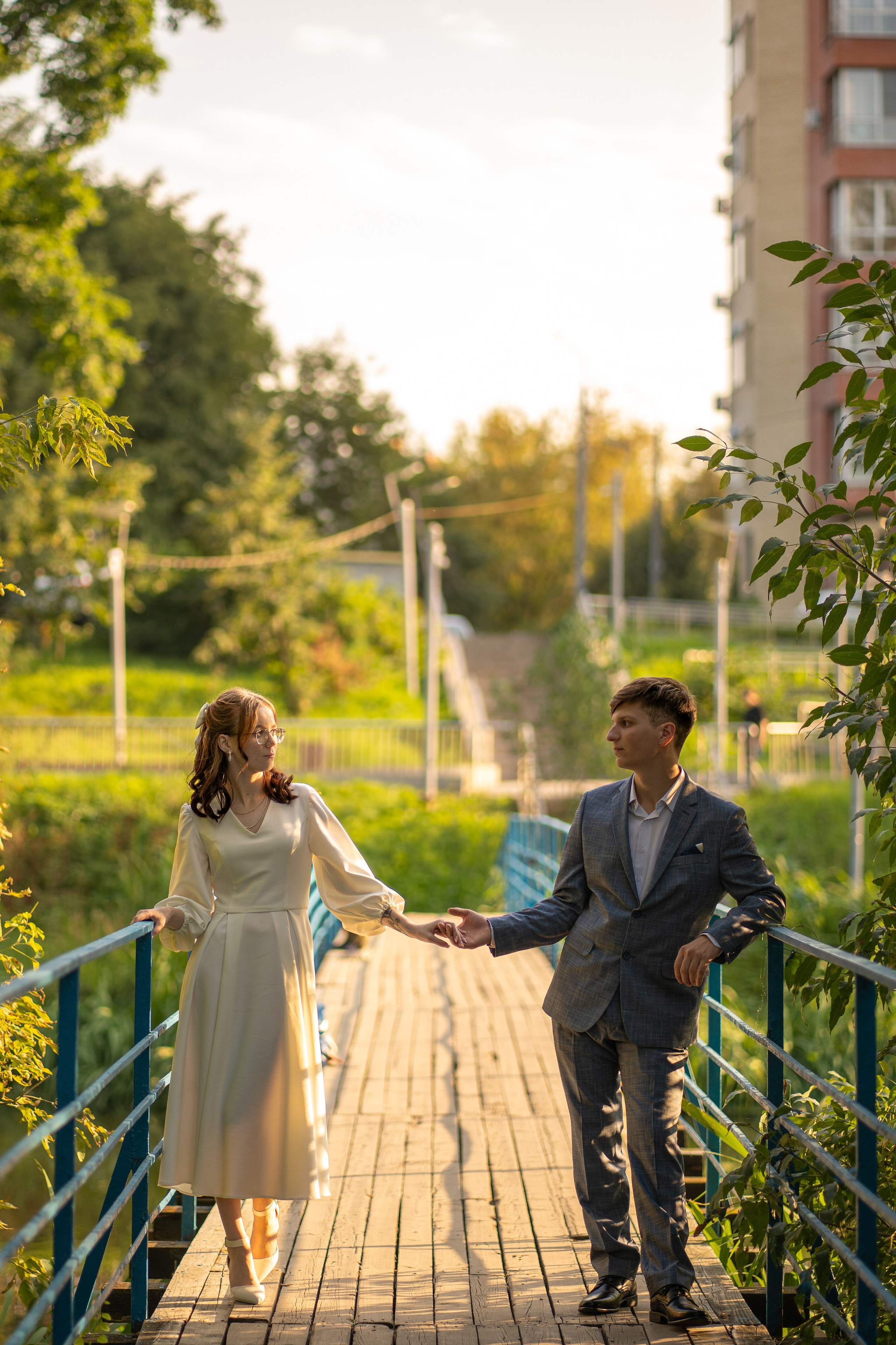 Жених и невеста держатся за руки на мосту