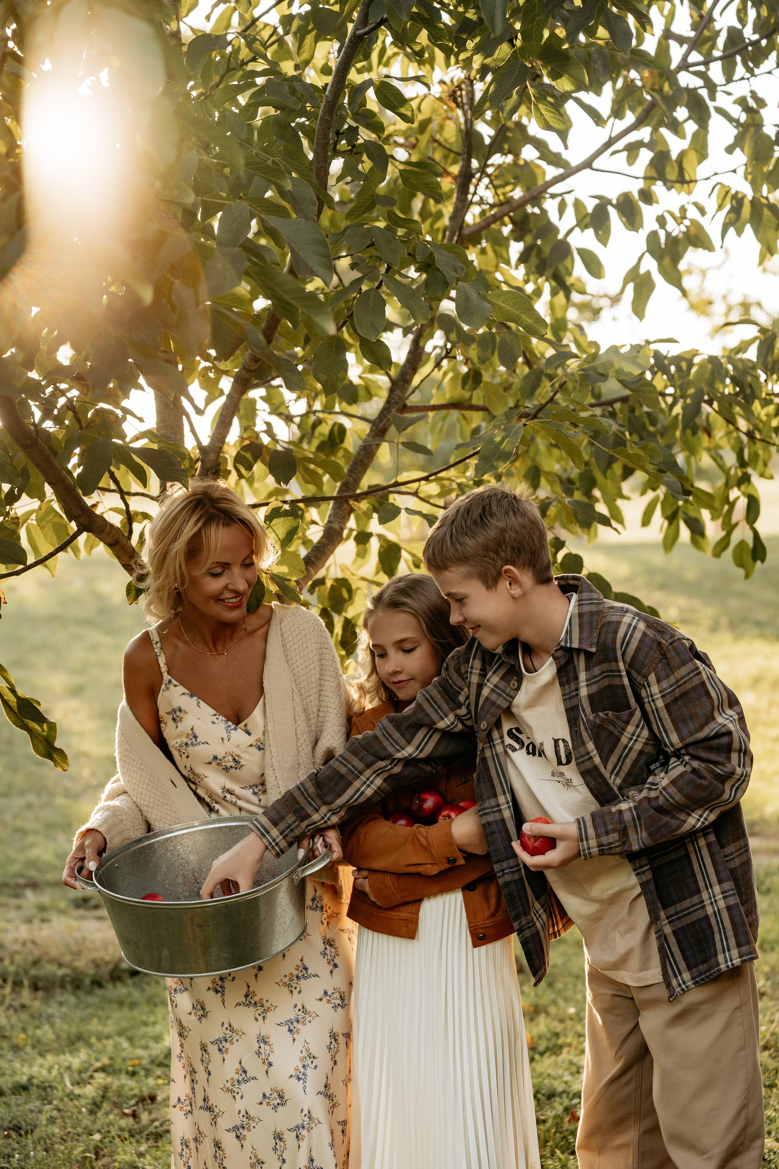 Фотограф в Анапе предлагает семейную фотосессию на эко-ферме. Кадр: семья в яблоневом саду.