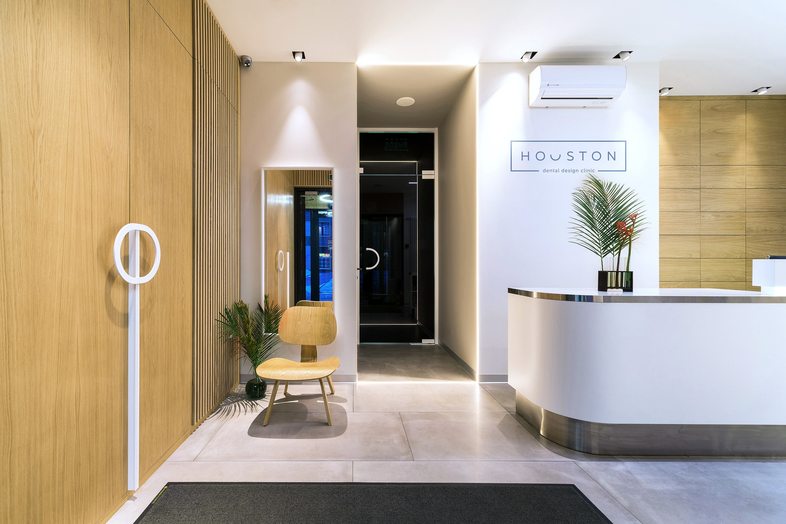 дизайн интерьера стоматологической клиники выполнен в современном минималистичном стиле с теплой домашней атмосферой. Текстуры дерева, наливной пол, яркие акценты, чистота линий, модульная сетка, стеклянные перегородки