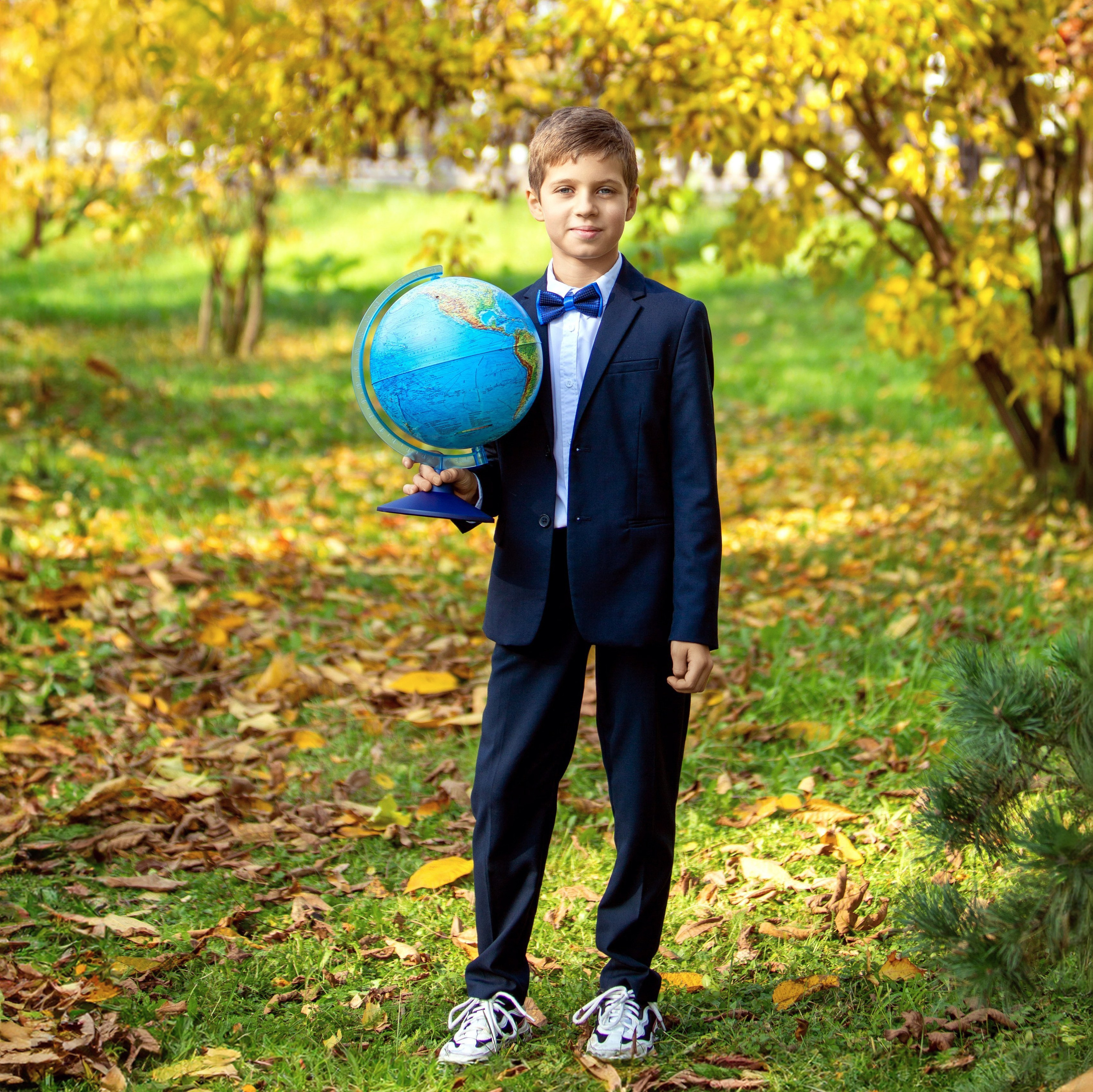 Мальчик держит глобус, портрет школьника на фоне карты