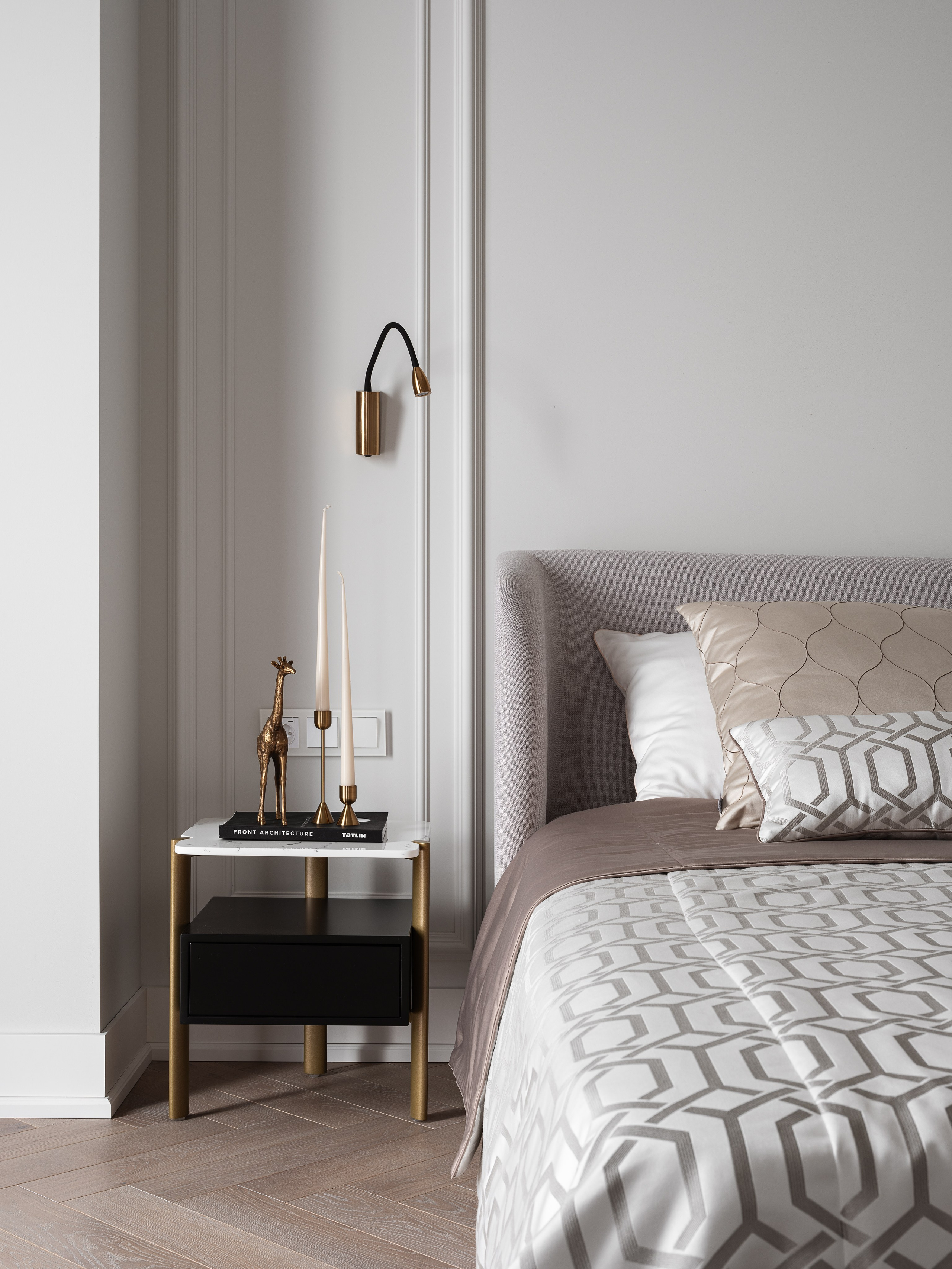 Деталь интерьера спальни: прикроватная тумба с мраморной столешницей и золотыми ножками, настенные светильники, бронзовый декоративный жираф и свечи. Спальня создана дизайнером Василиссой Бачевой, стилист Наталья Якушева, фотограф Сергей Денисенко.