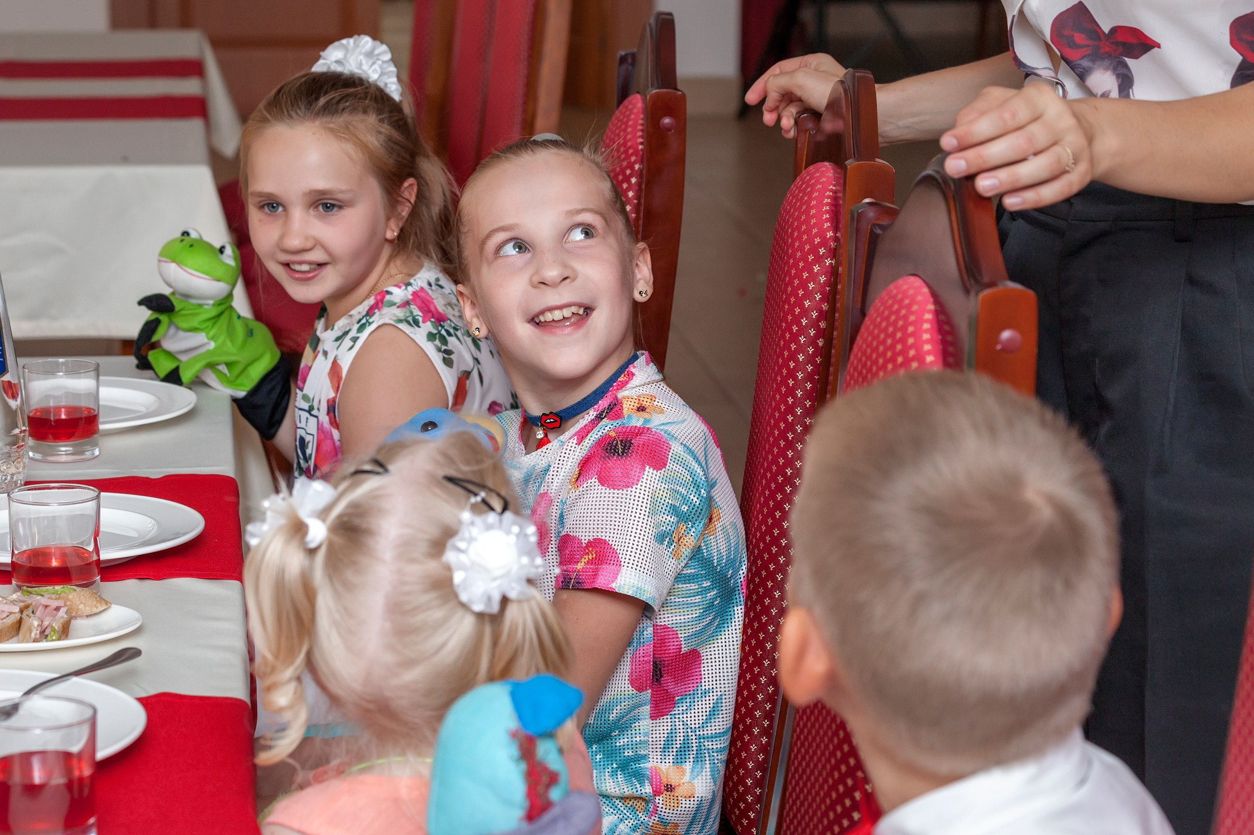 Портрет девочки в цветной кофте за столом на детском празднике.