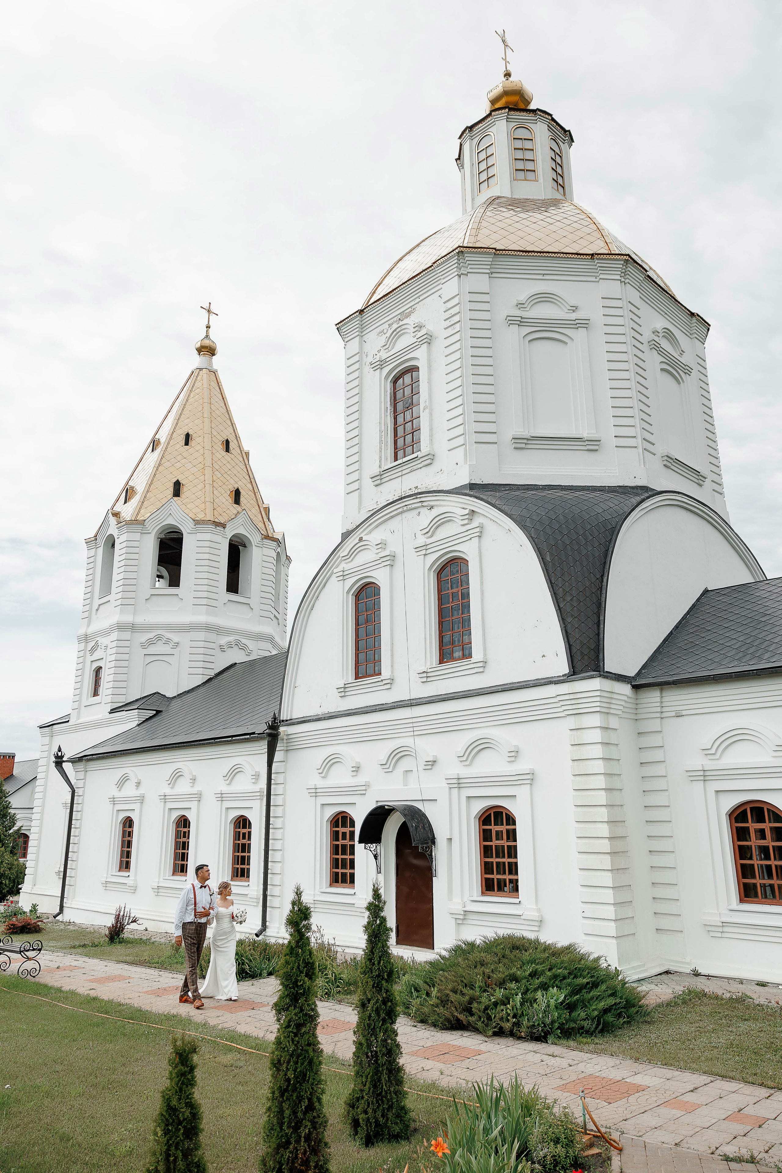 Жених и невеста гуляют  на фоне церкви на свадебной фотосесии в Воронеже