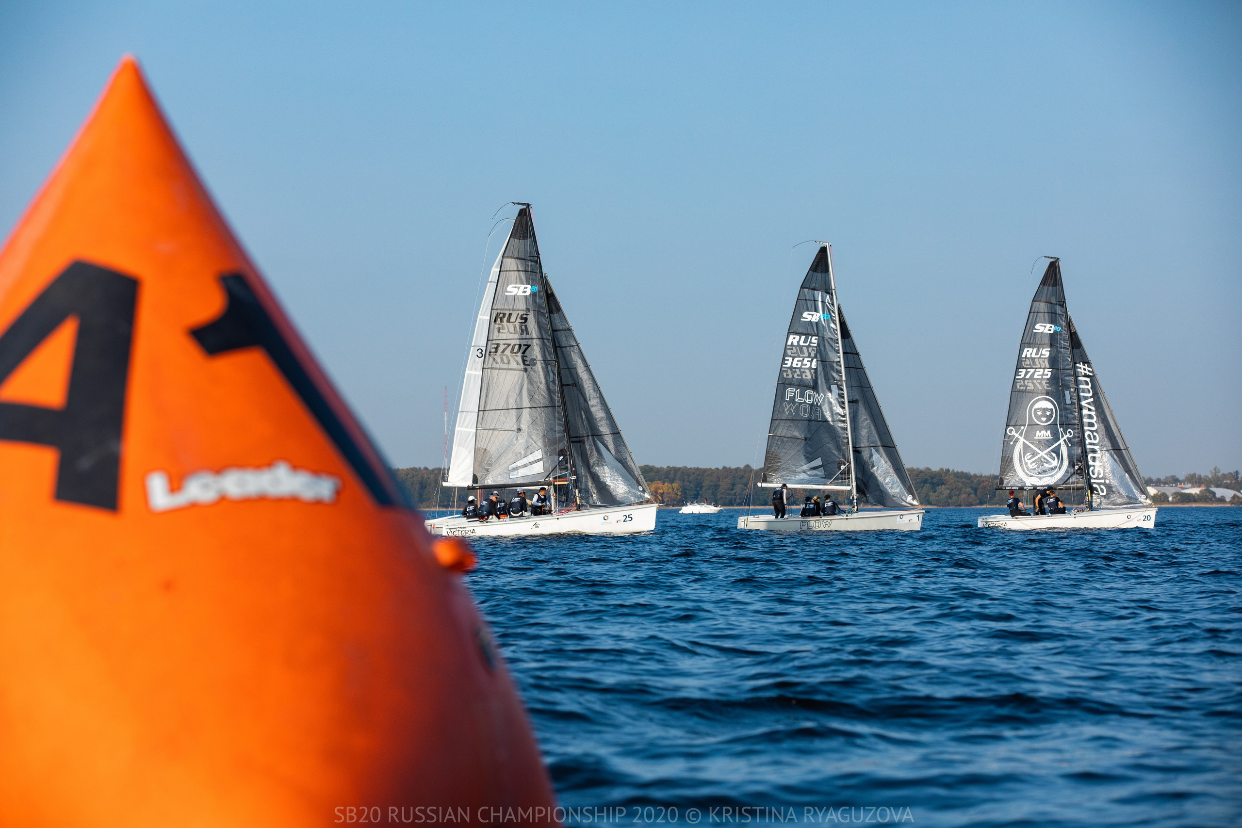 Яхты класса SB20 в ряд и оранжевый надувной знак на регате. Правила парусных гонок.