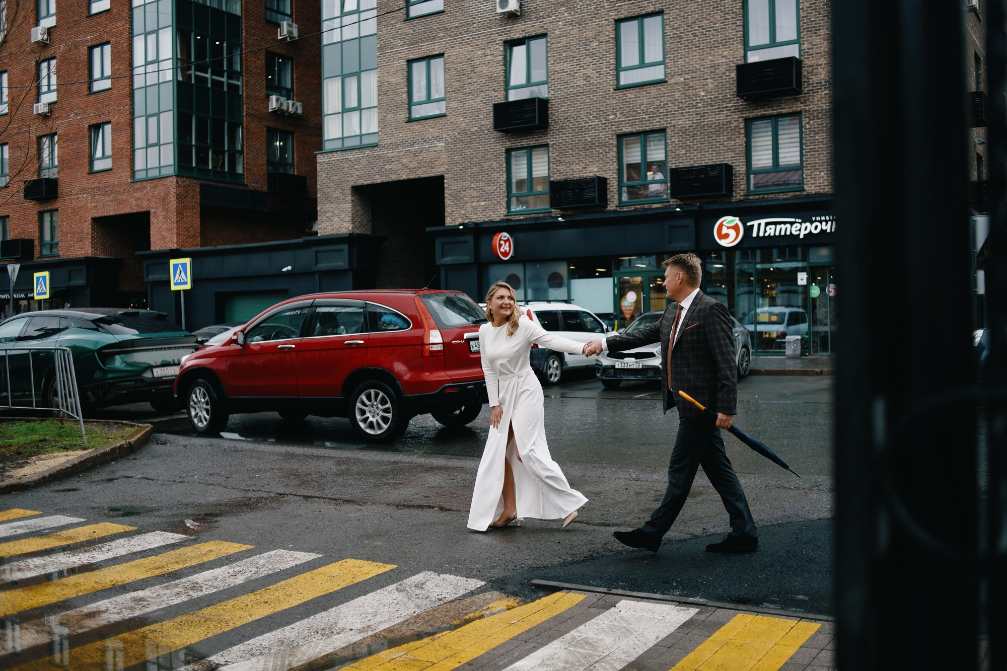 Жених и невеста идут по городской улице, стильная свадебная прогулка в пасмурную погоду