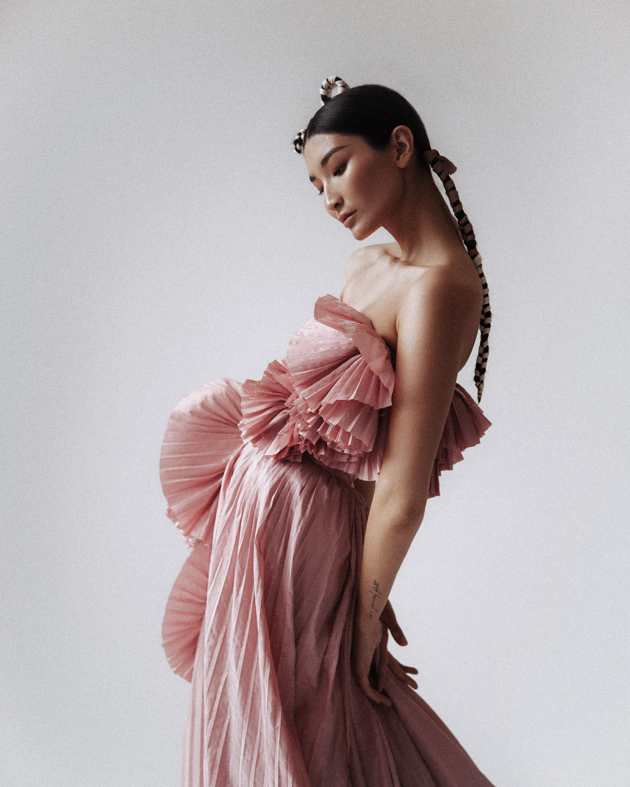 модель азиатской внешности позирует стоя убрав руки за спину