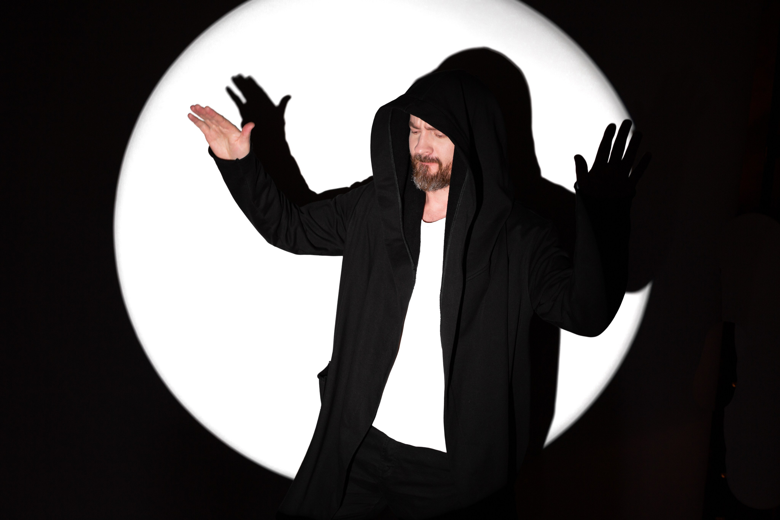 Мужчина с бородой в мантии в белом круге света