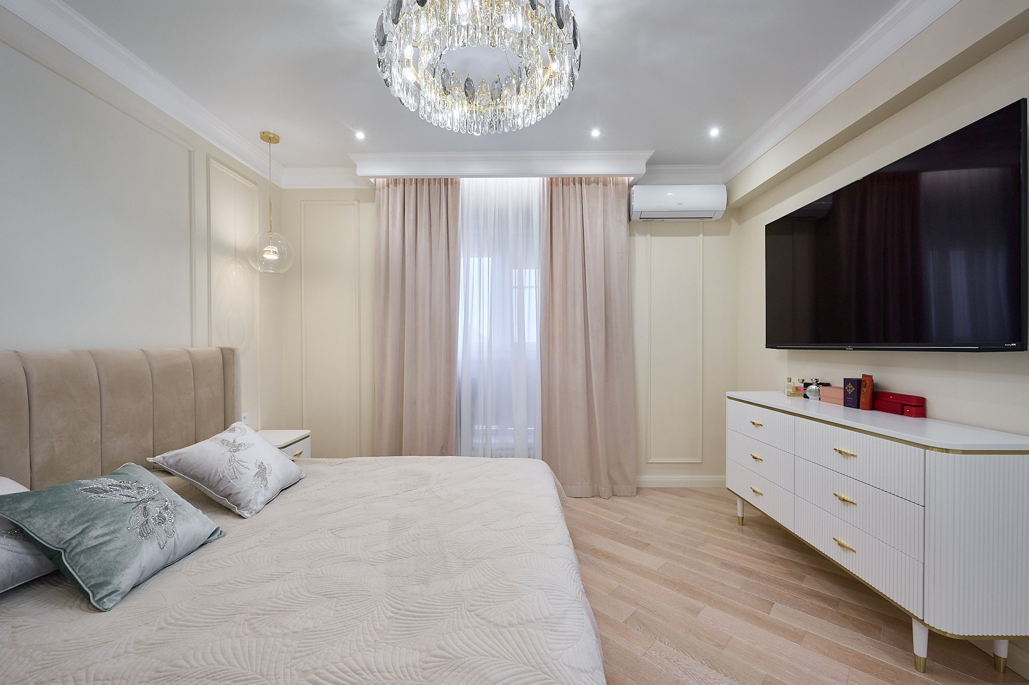 комната в светлых оттенках с бежевой шторой белой кроватью белая тумбочка телевизор 