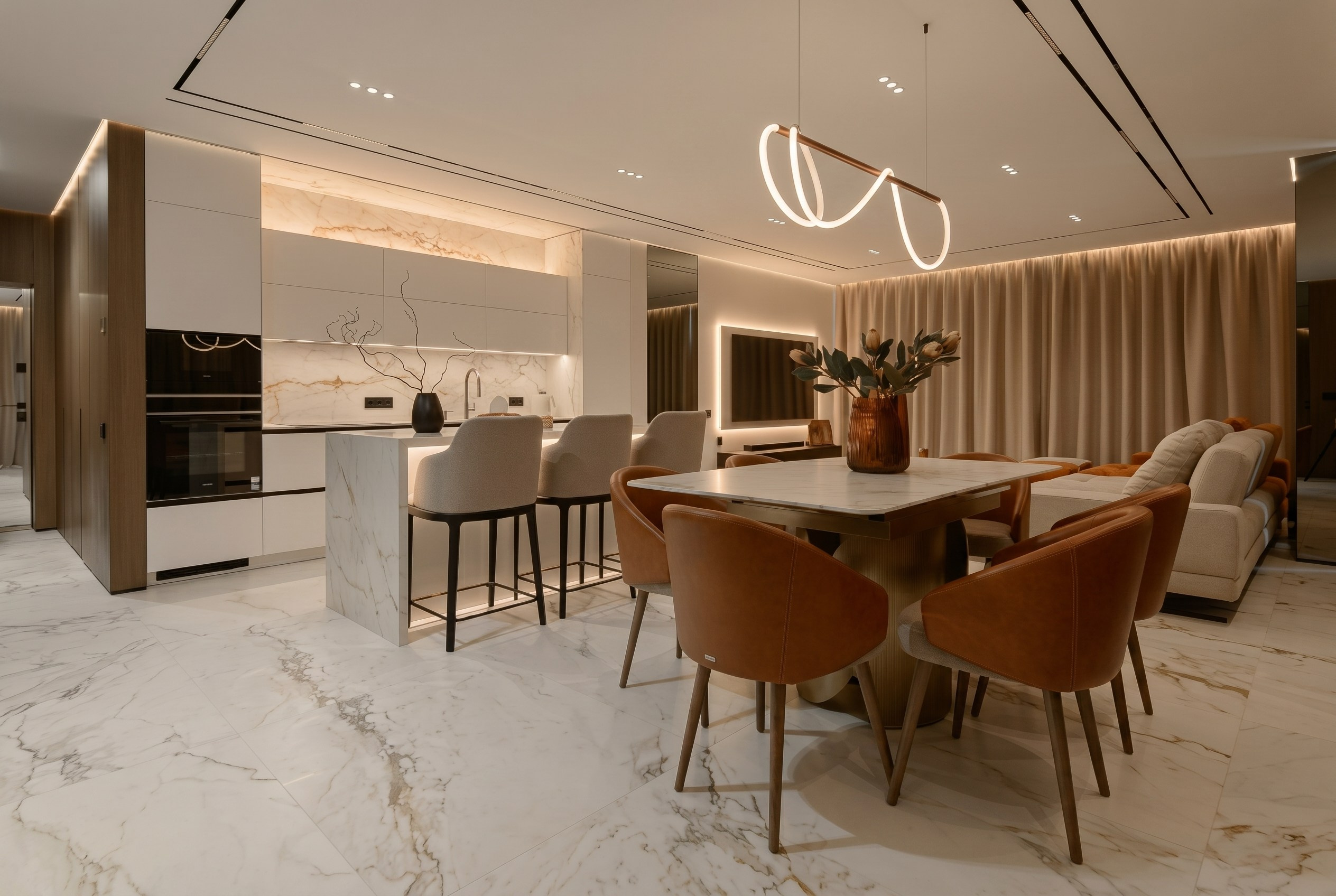 Вечерний интерьер кухни-гостиной и столовой в квартире 116 м² от Валерии Котович: многоуровневое освещение, обеденная группа с терракотовыми креслами и мраморная отделка пола в Краснодаре.