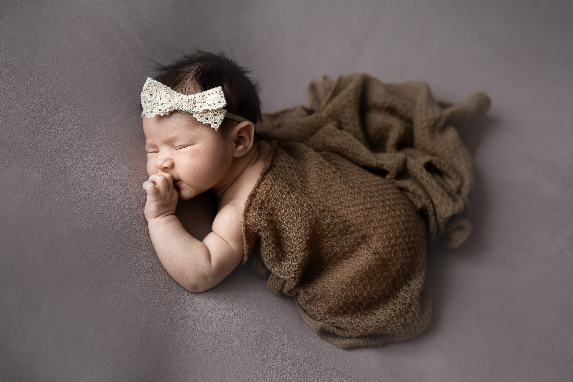 Сонный младенец укрыт коричневым пледиком.