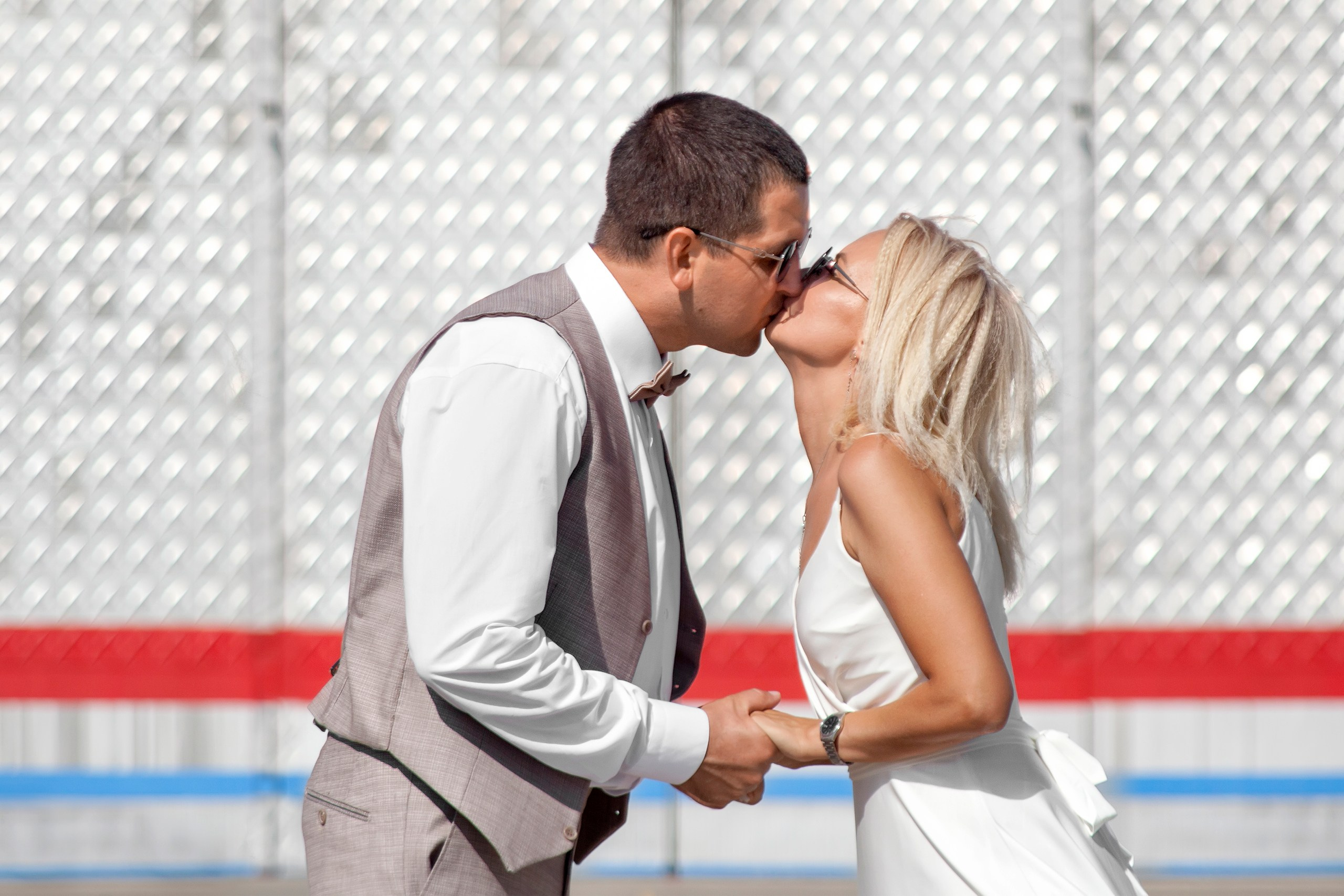 Жених и невеста целуются на фоне металлической стены - свадебная прогулка