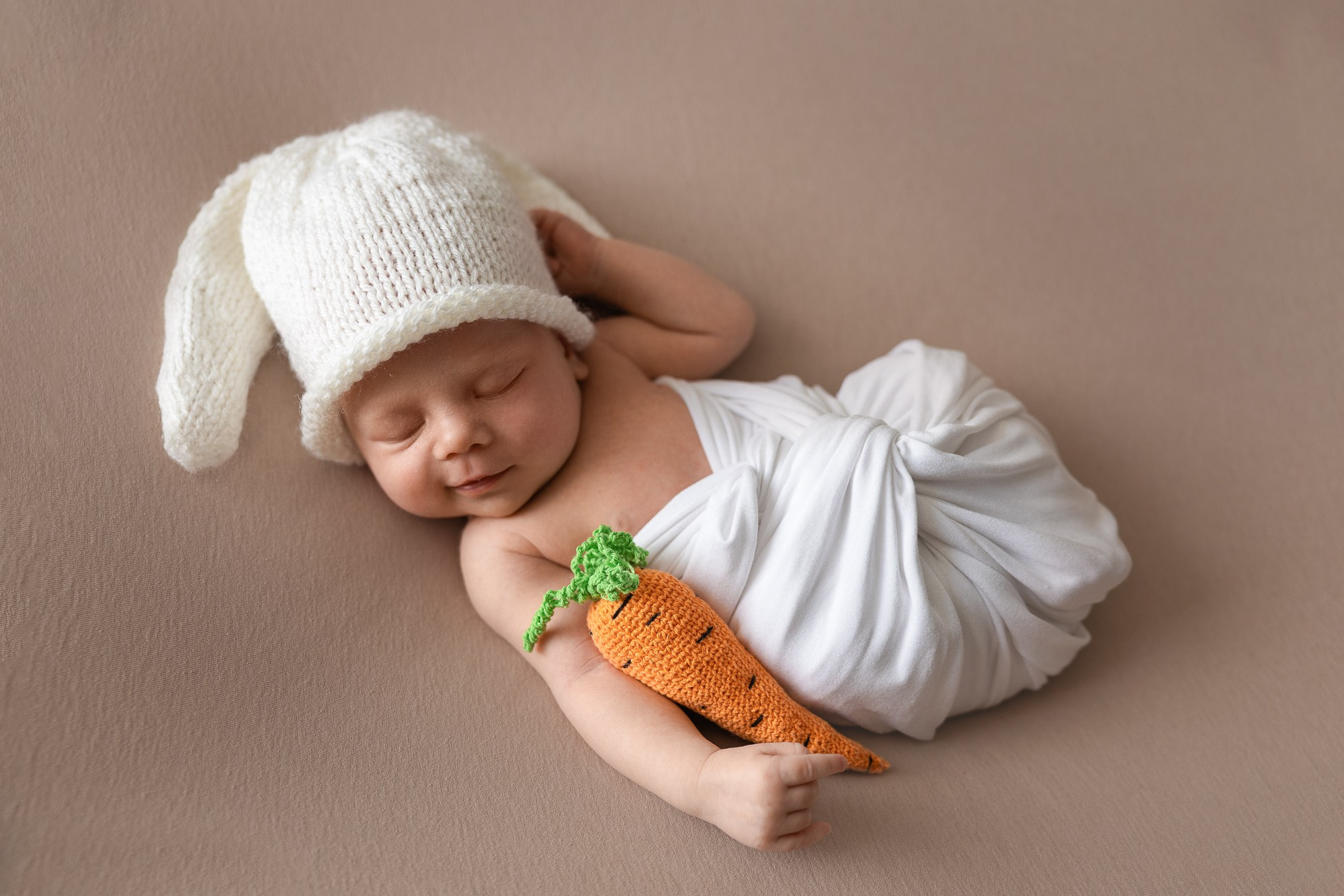 Новорожденный малыш в костюме зайчика с морковкой.