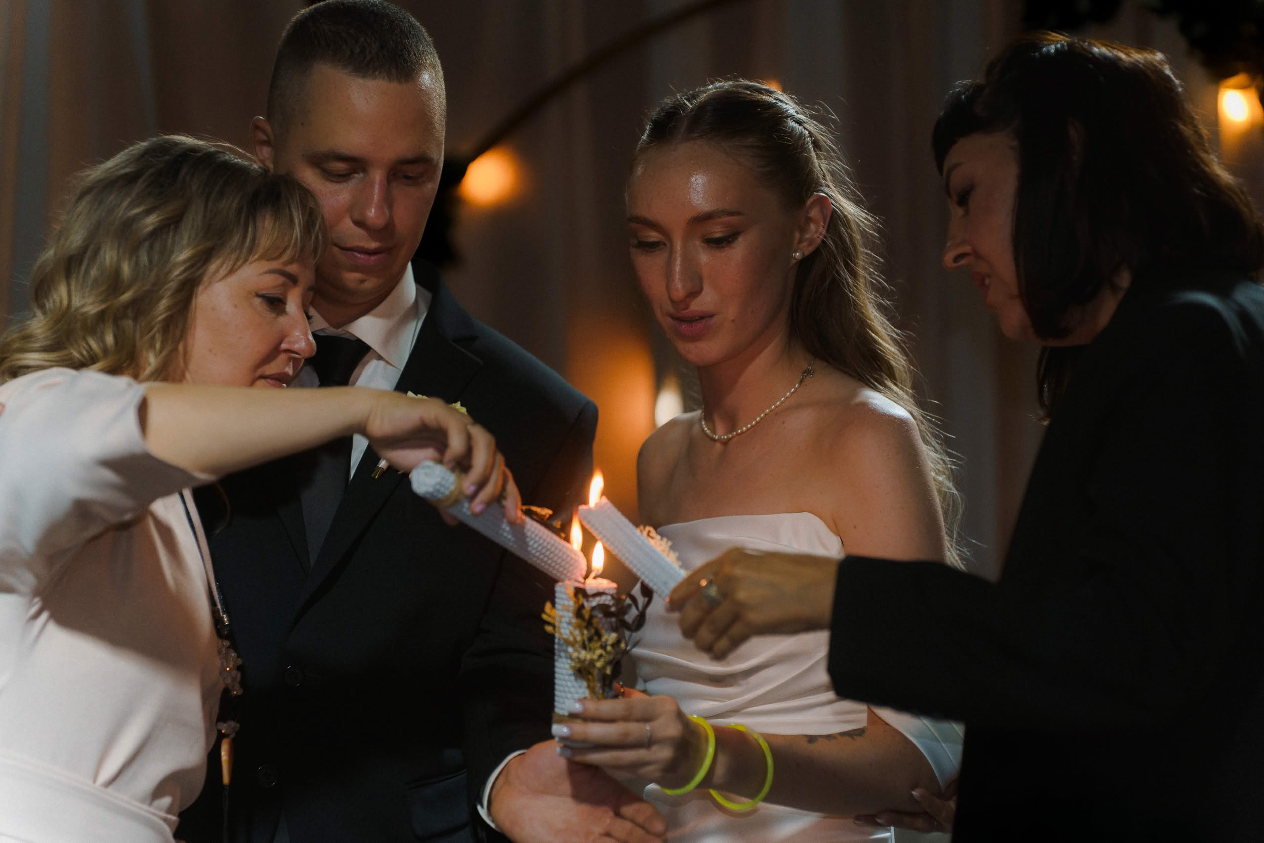 Родители и молодожёны вместе зажигают свадебную свечу