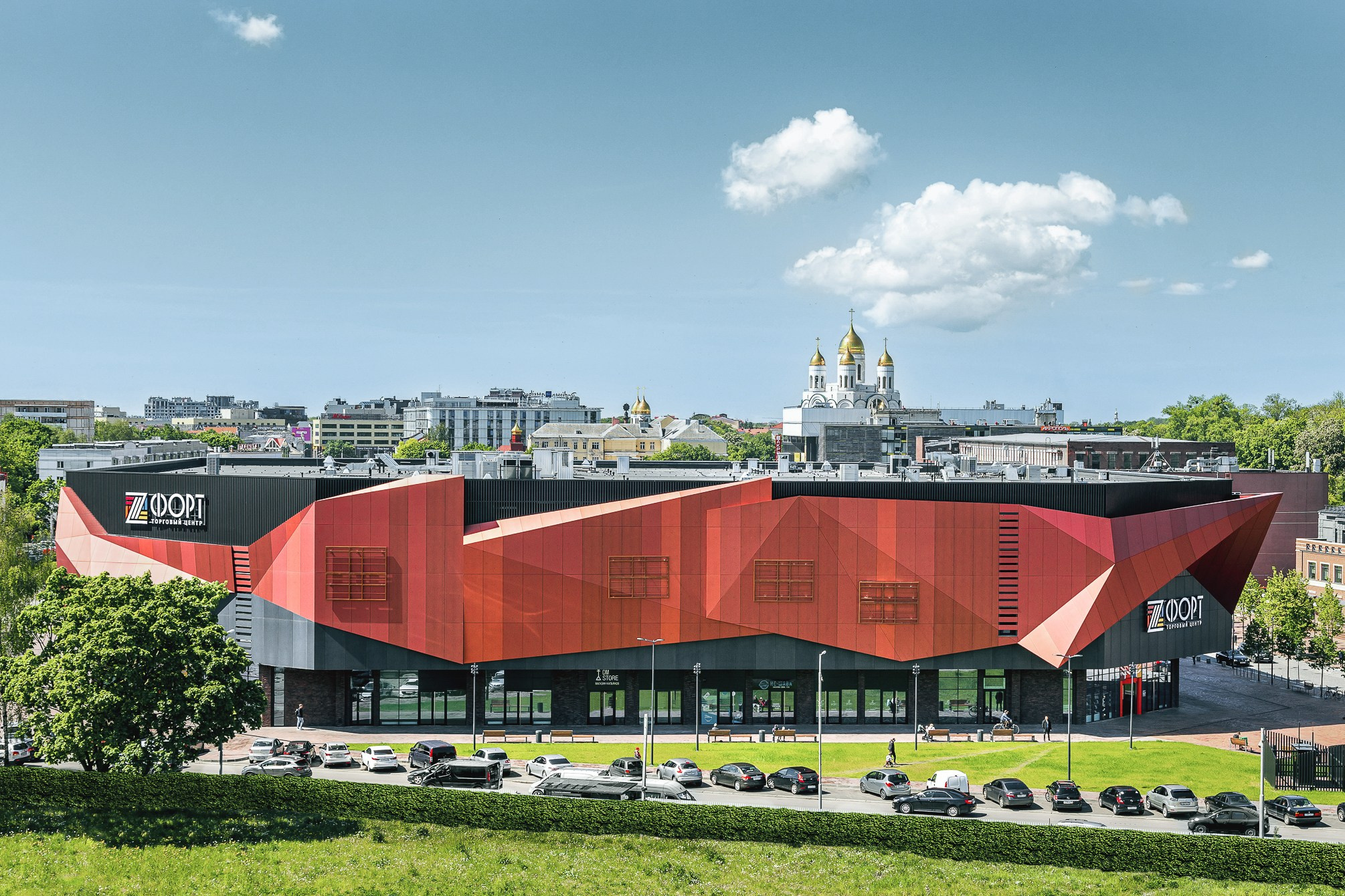 Фасад здания в кирпичных оттенках с серым посреди улицы.