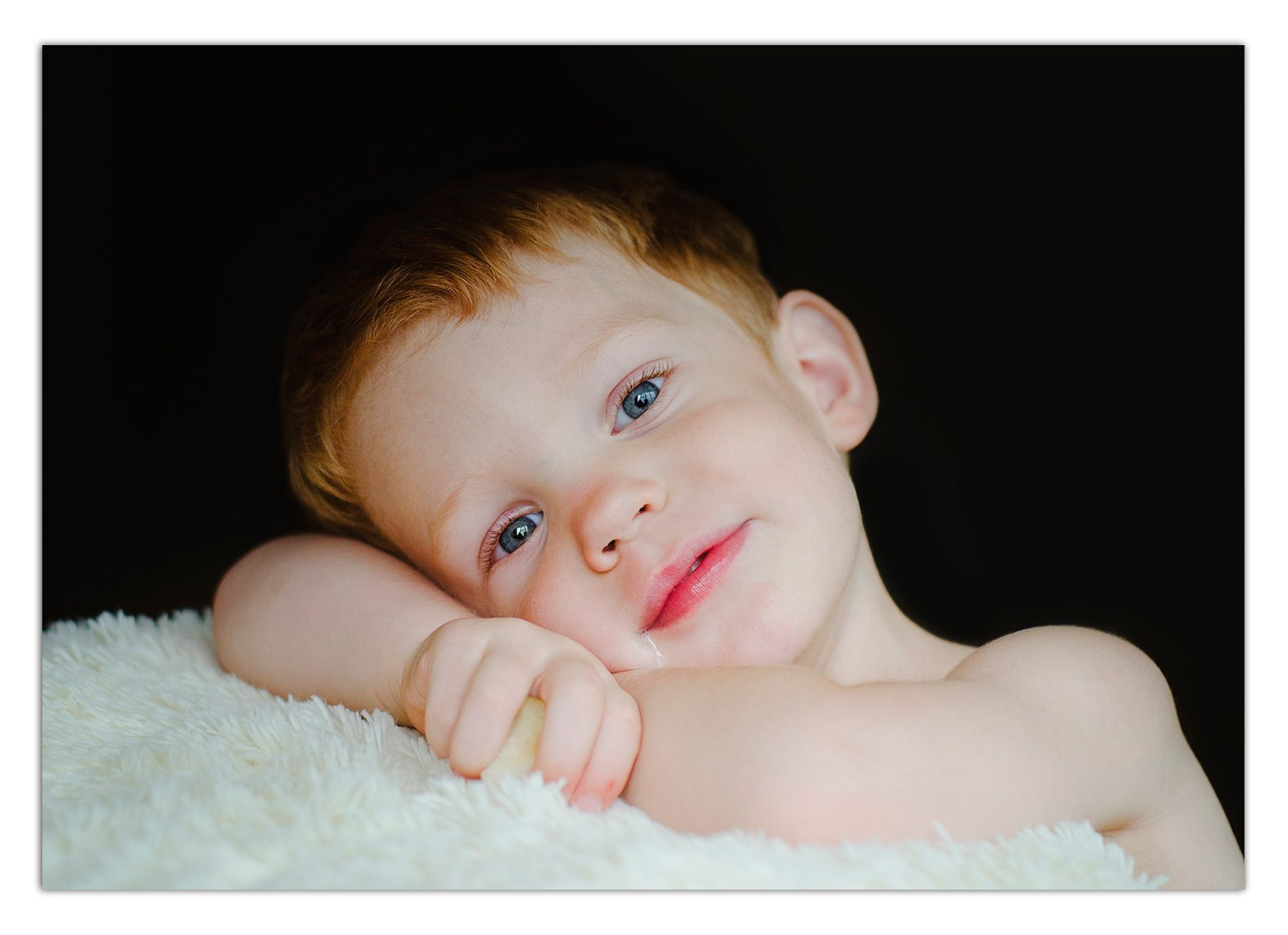 Фотосессия детей - ребёнок лежит на пушистом пледе с яблоком, тихая уютная атмосфера.