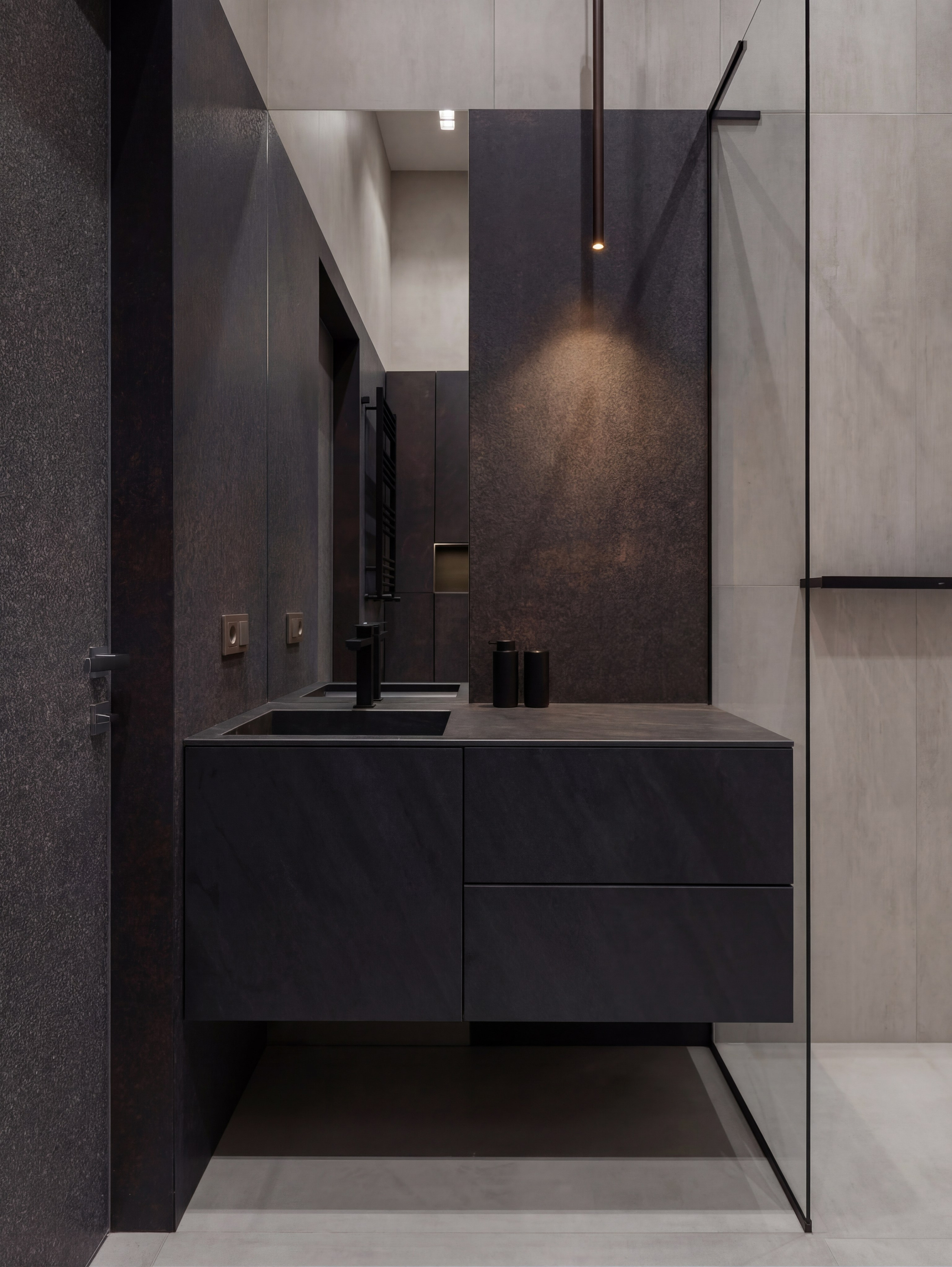 Минималистичный дизайн санузла от Валерии Котович: черная парящая тумба с интегрированной раковиной, высокие зеркала, стены с текстурой темного металла и точечное освещение в доме у воды.