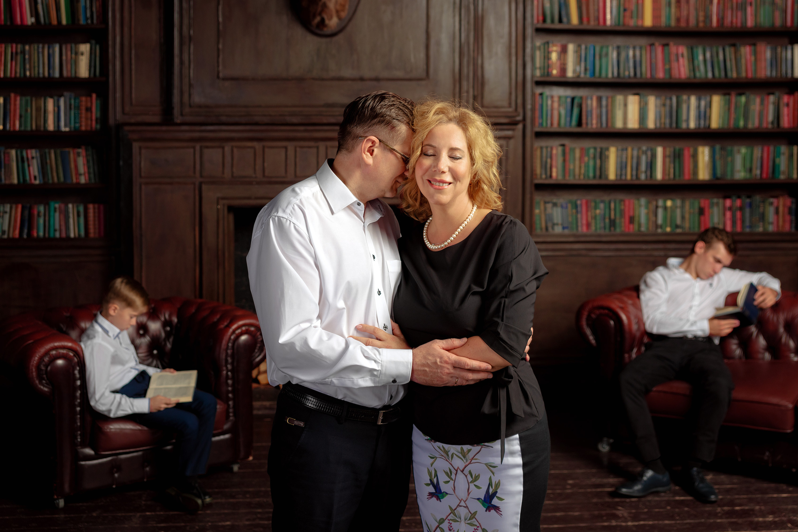 Родители обнимаются на переднем плане, на заднем сидят дети