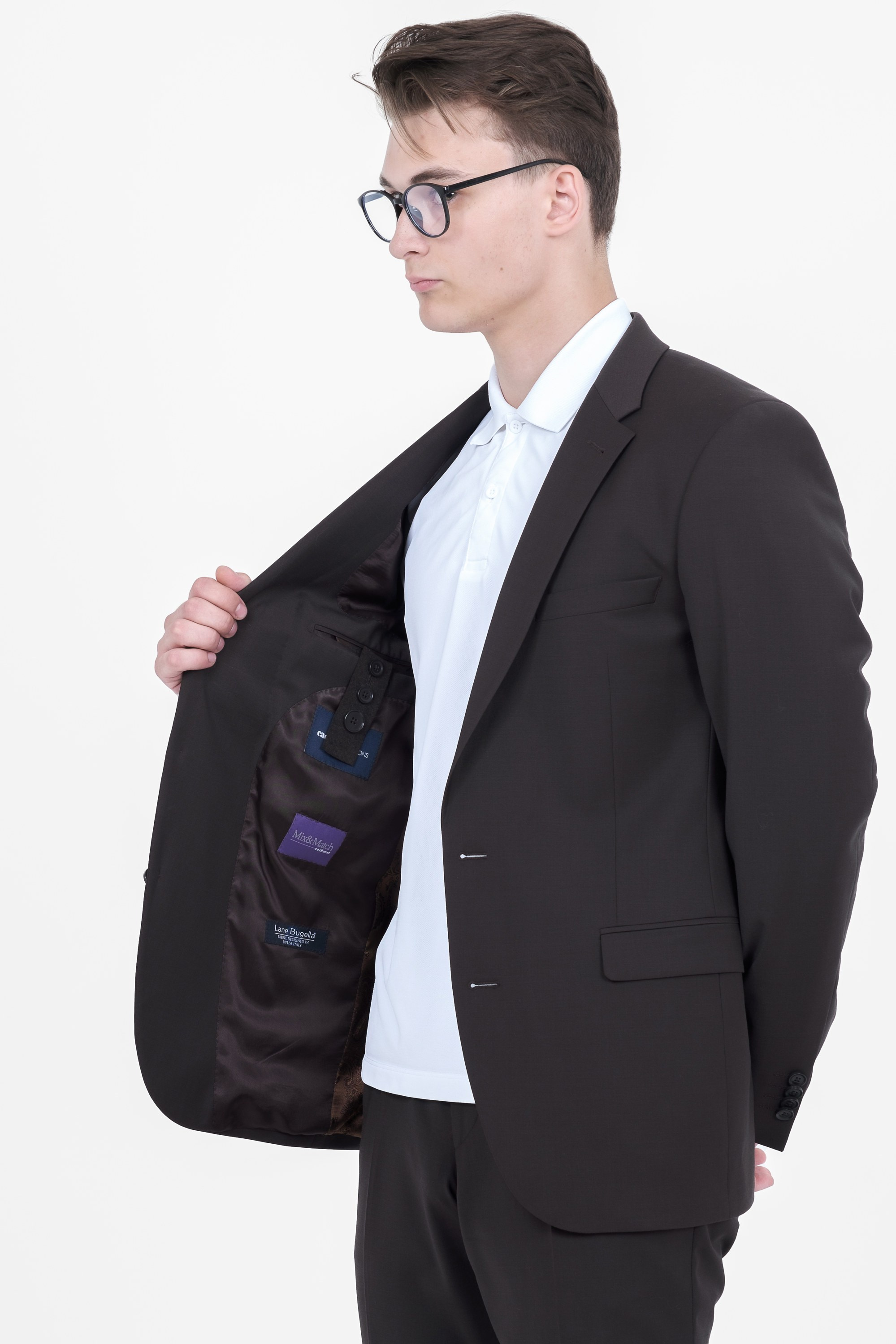 Молодой человек стоит в чёрном пиджаке в очках.  Фото для маркетплейсов