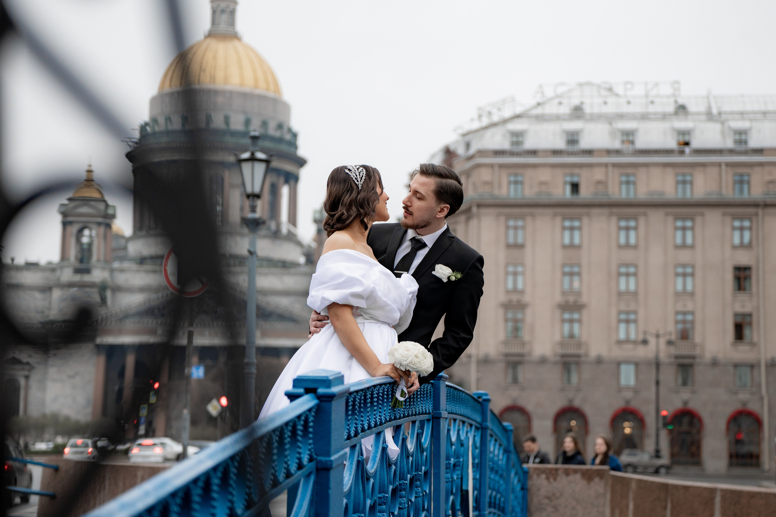 Свадебная фотосессия рядом с Исаакиевским собором. Пара обнимается на синем мосту на фоне собора. Самые популярные места для свадебной фотосессии в Санкт-Петербурге