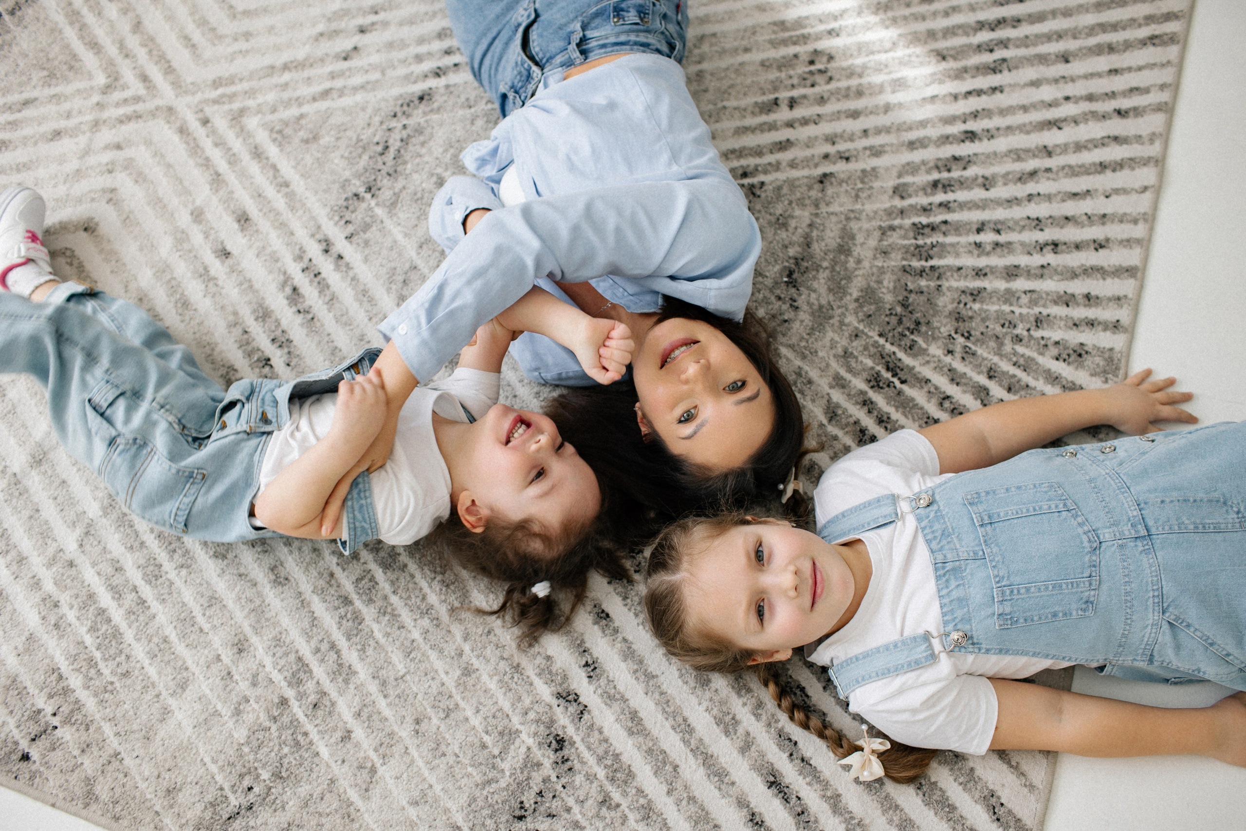 мама с дочками лежит на ковре, улыбки и смех 