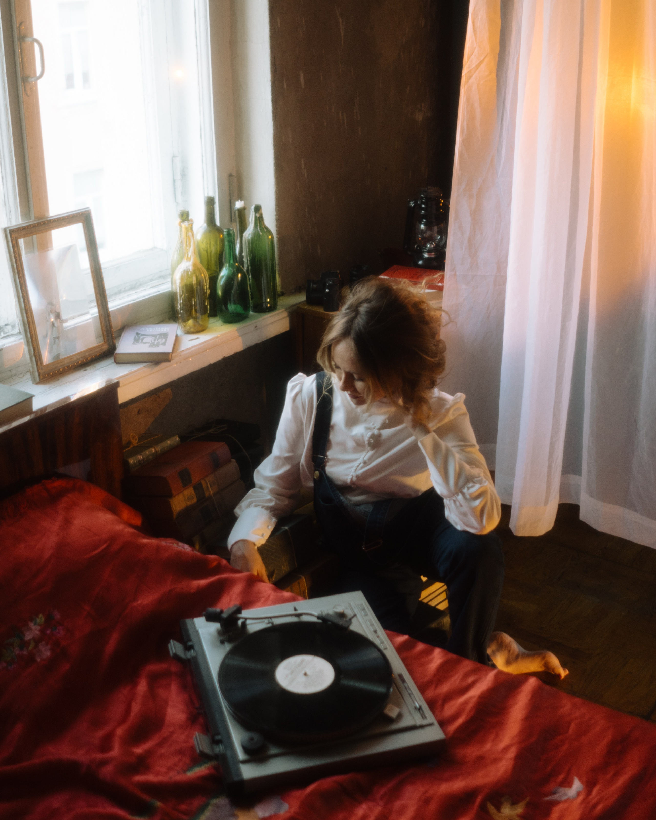 Беременная в белой рубашке у окна: кровать с красным покрывалом и виниловый проигрыватель — стильная фотосессия беременности в ретро-студии СПб.