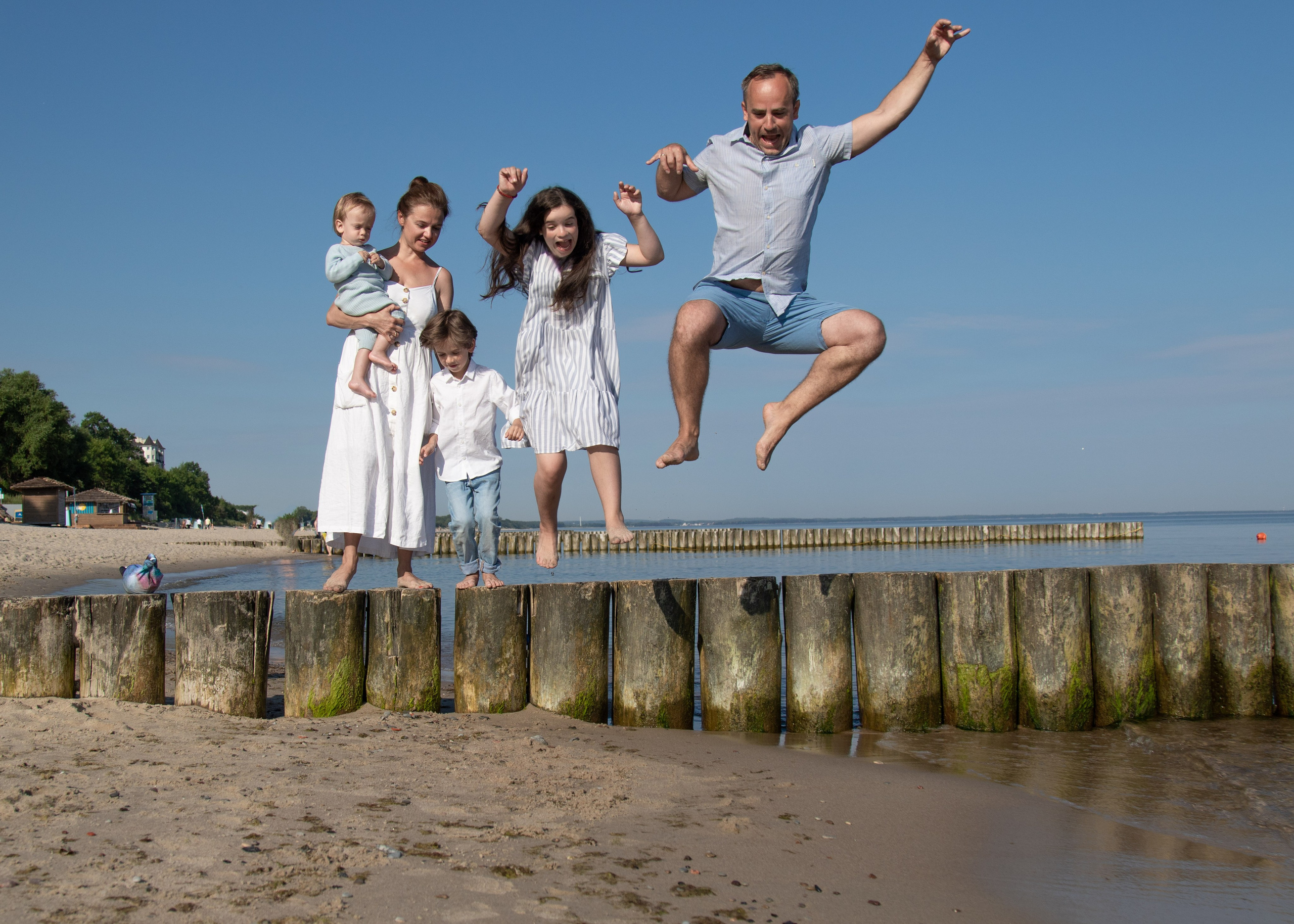 веселая семья прыгает в воду на пляже