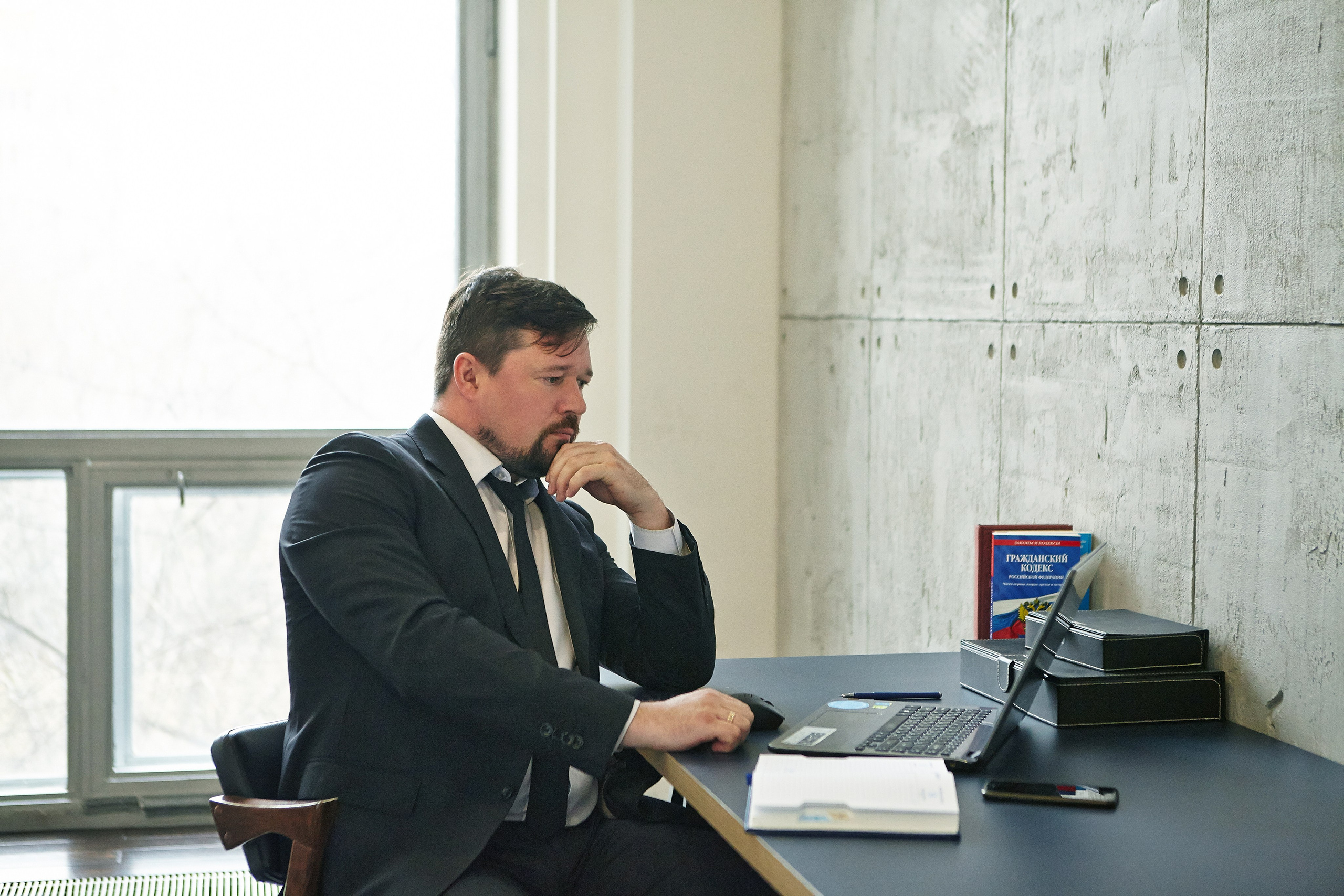 солидный мужчина сидит в стильном офисе с ноутбуком