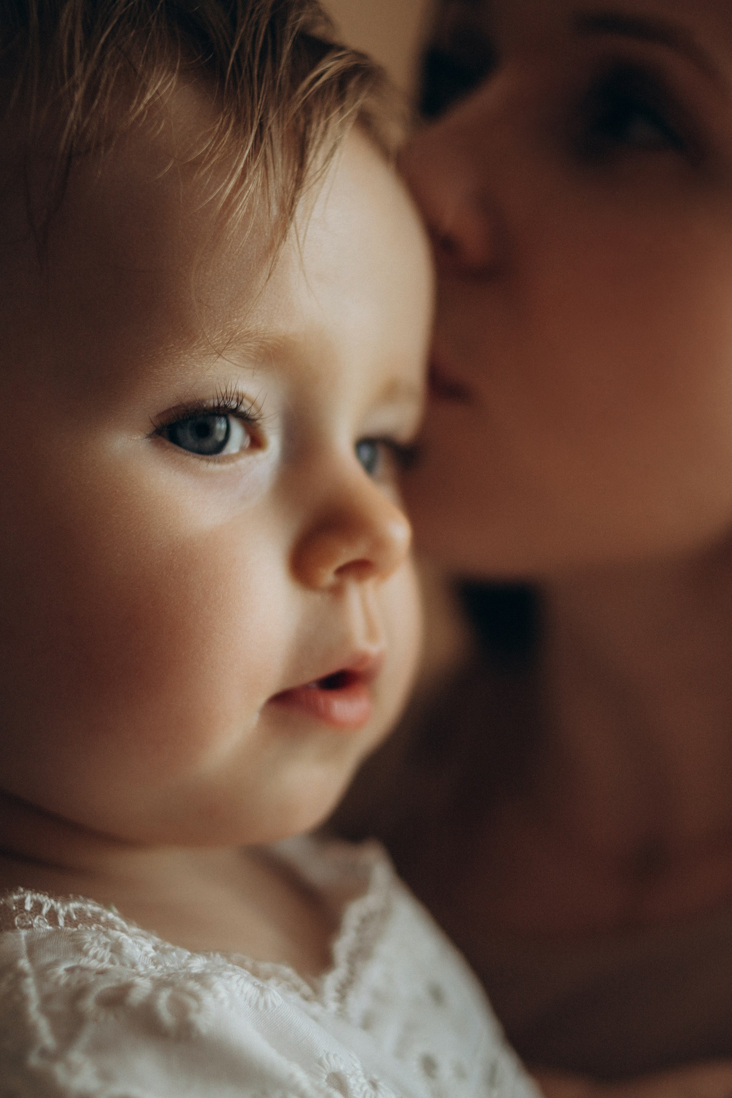 Мама нежно целует дочку на домашней фотосессии