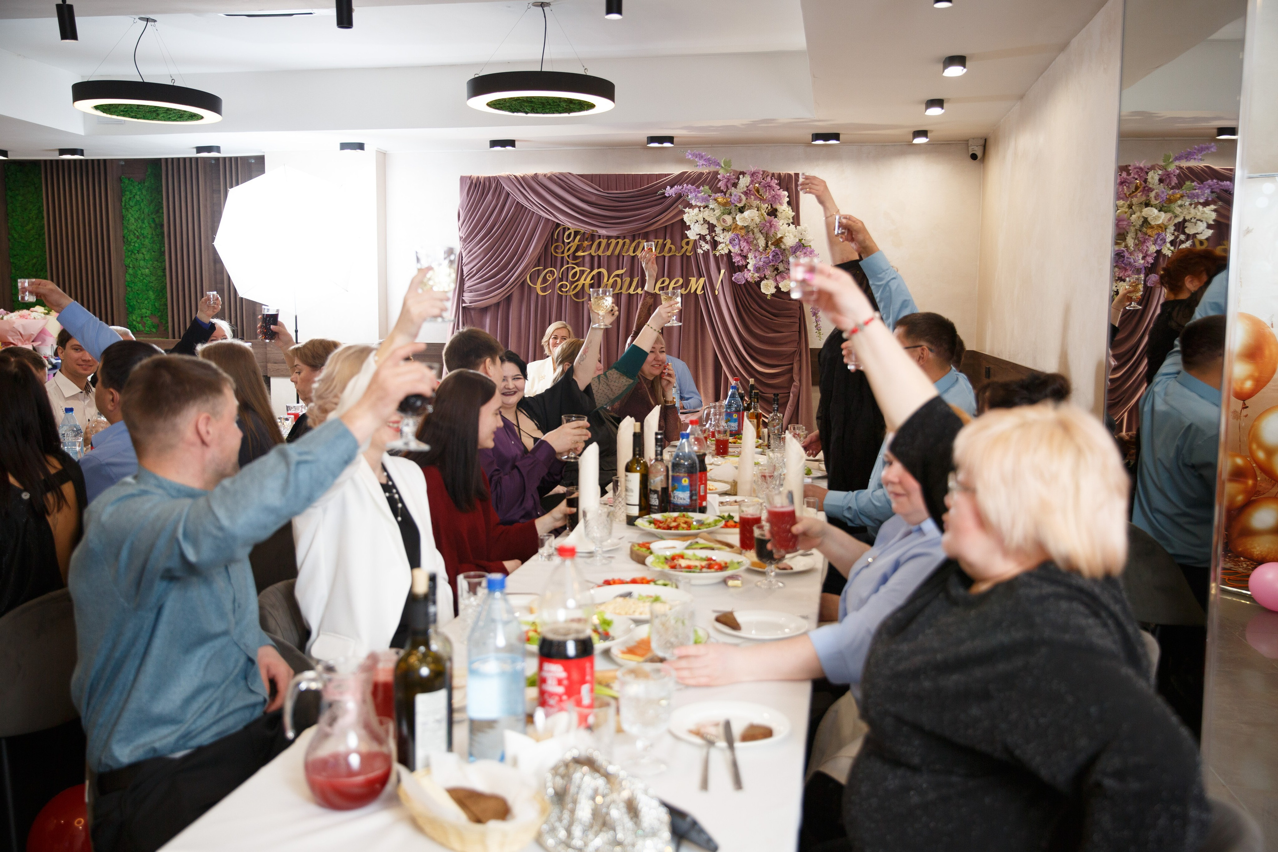 Гости аплодируют стоя, праздничная атмосфера.