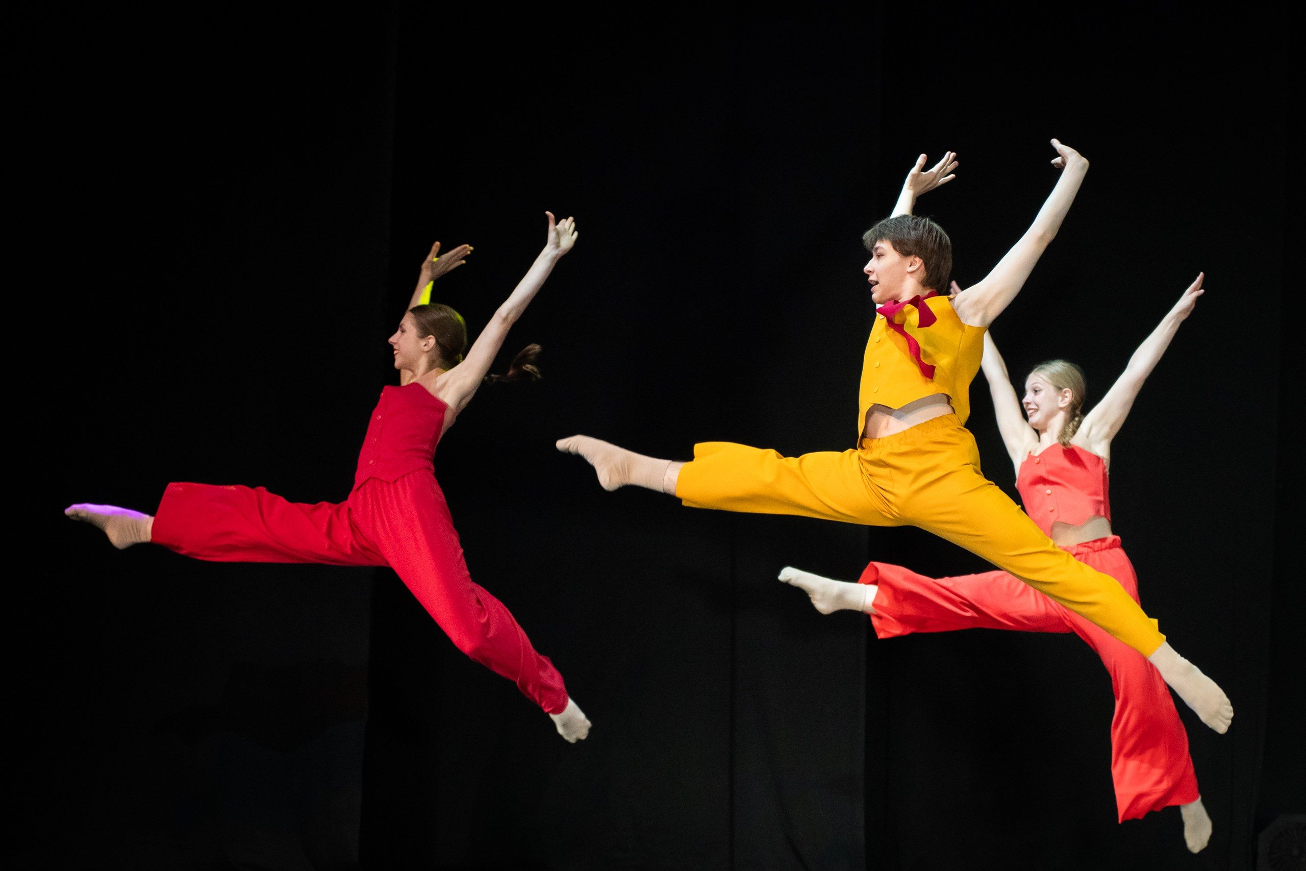 Танцоры в красных и жёлтых костюмах в прыжке — отчётный концерт Smart Dance
