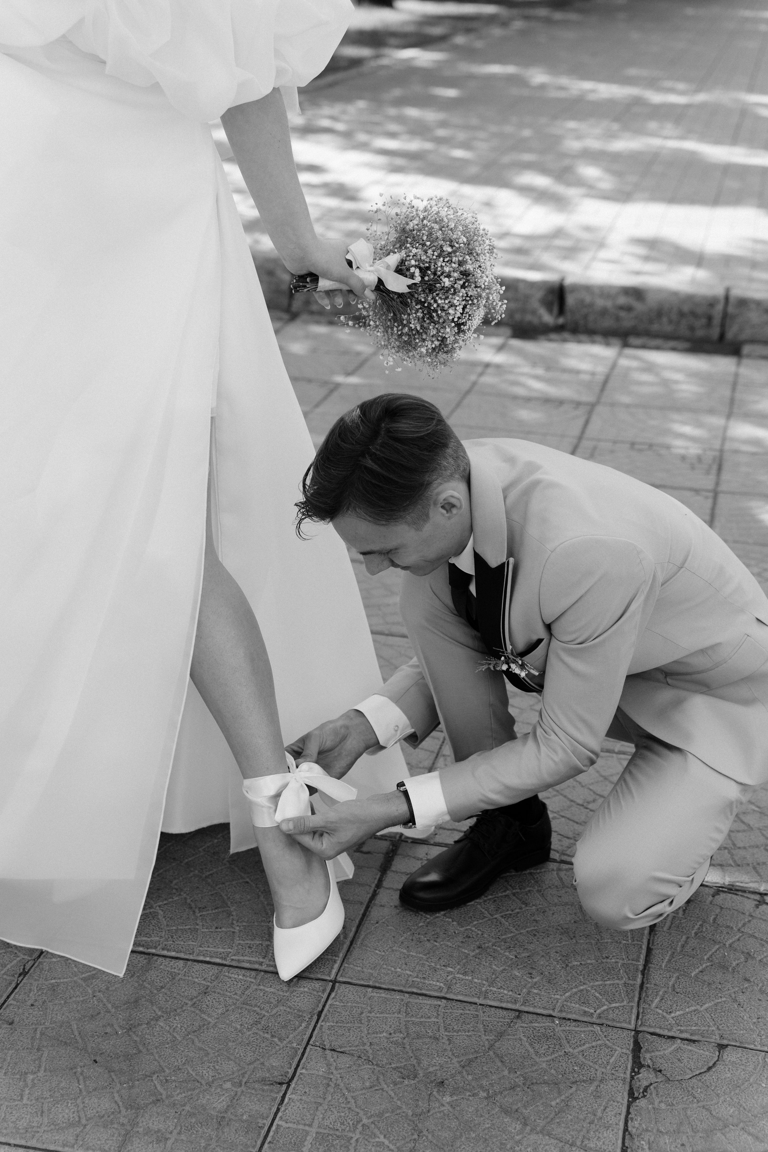 Жених застегивает туфлю невесте на съемке