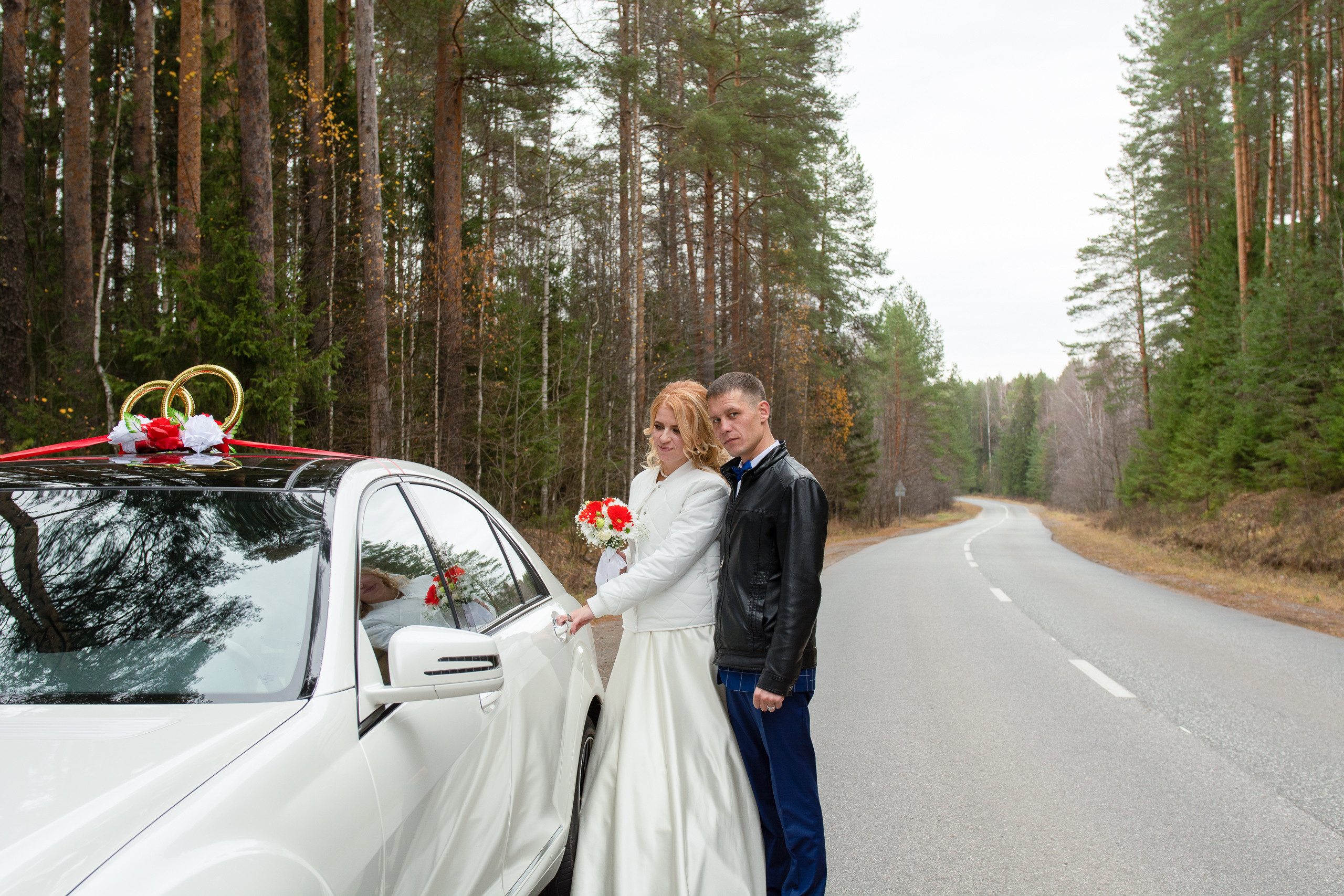 Свадебная фотосессия по дороге в ЗАГС: жених и невеста стоят рядом с автомобилем 