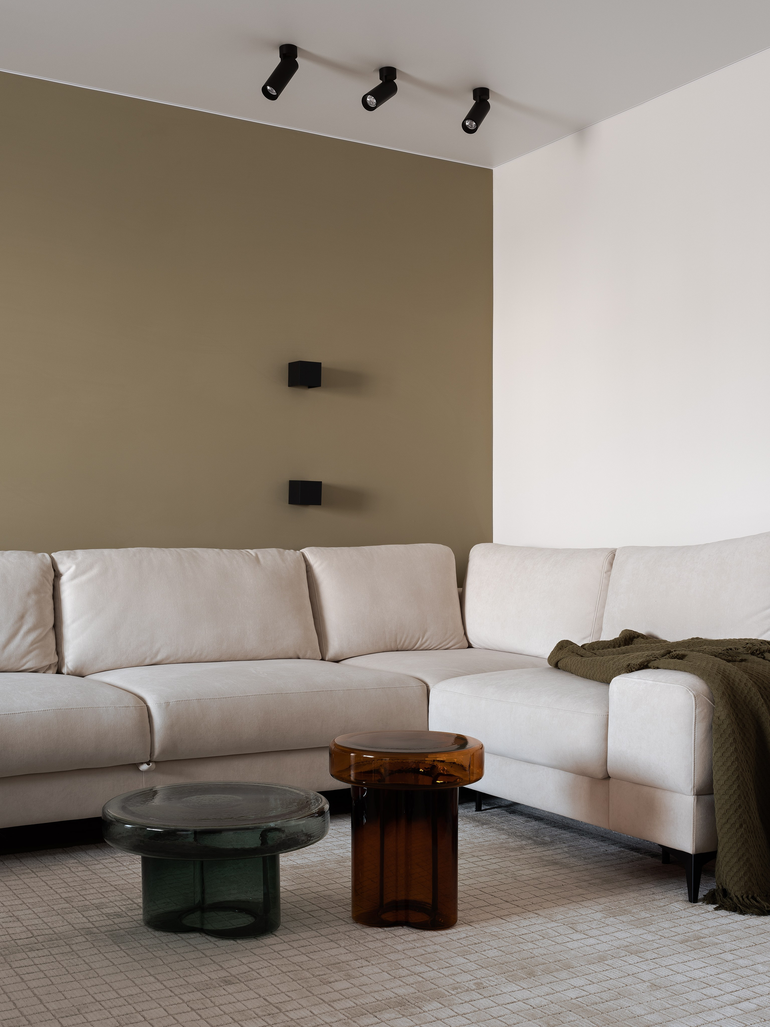 Современная гостиная с акцентной оливковой стеной, бежевым угловым диваном и дизайнерскими стеклянными столиками; проект Екатерины Мищенко, фотограф Сергей Денисенко.