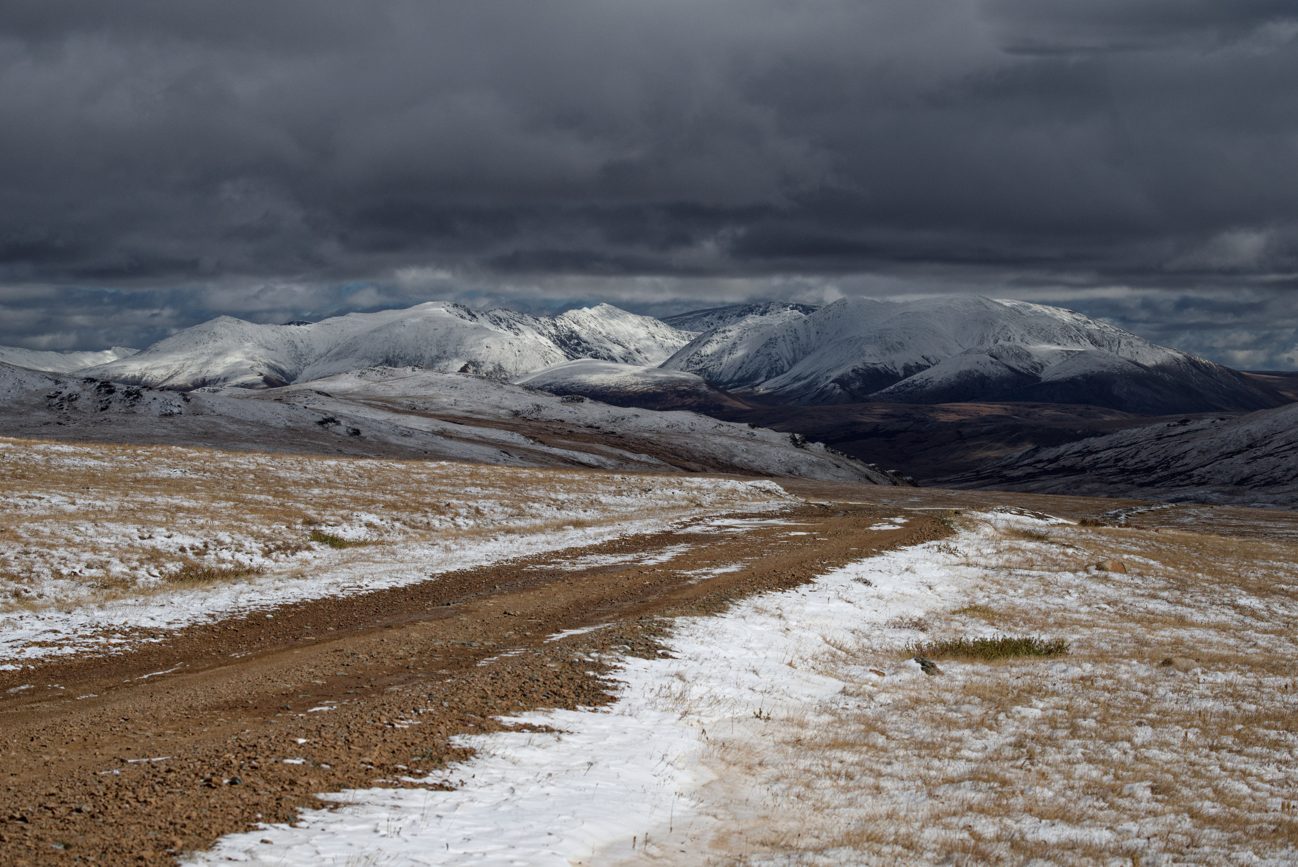 Осенняя дорога в горах по заснеженным склонам