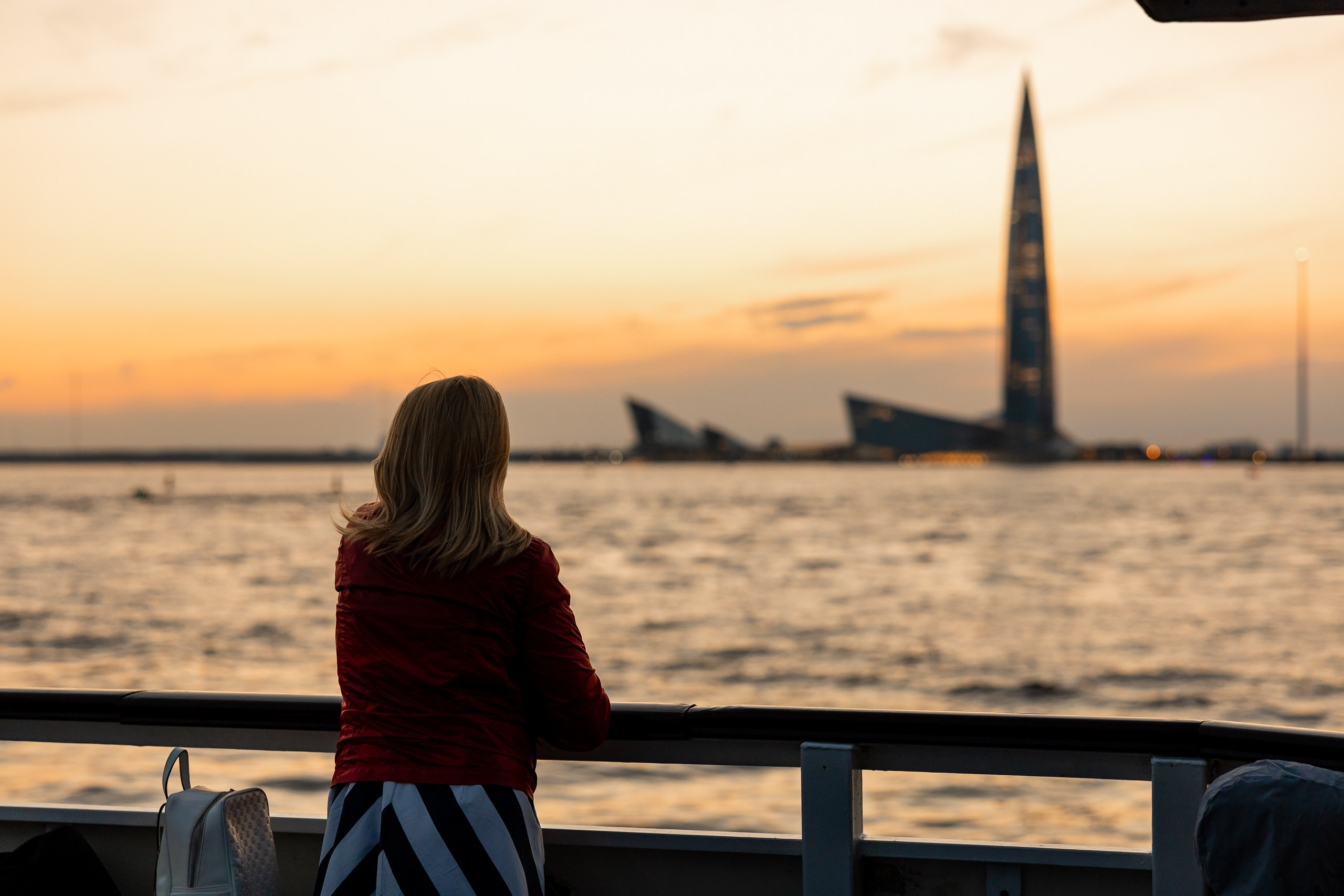 Девушка любуются видом с теплохода на Лахта-Центр на закате в Финском заливе