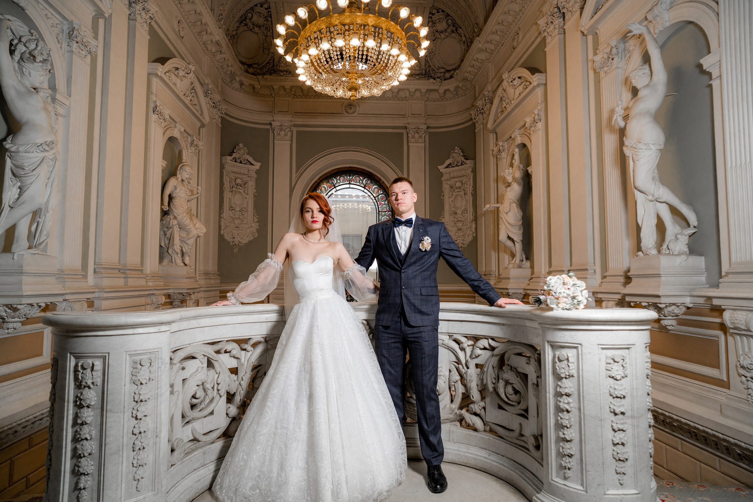 Свадебная фотосессия во Дворце Бракосочетания №1 Жених и невеста стоят на балконе и позируют фотографу. Фотография в темное время суток в загсе.