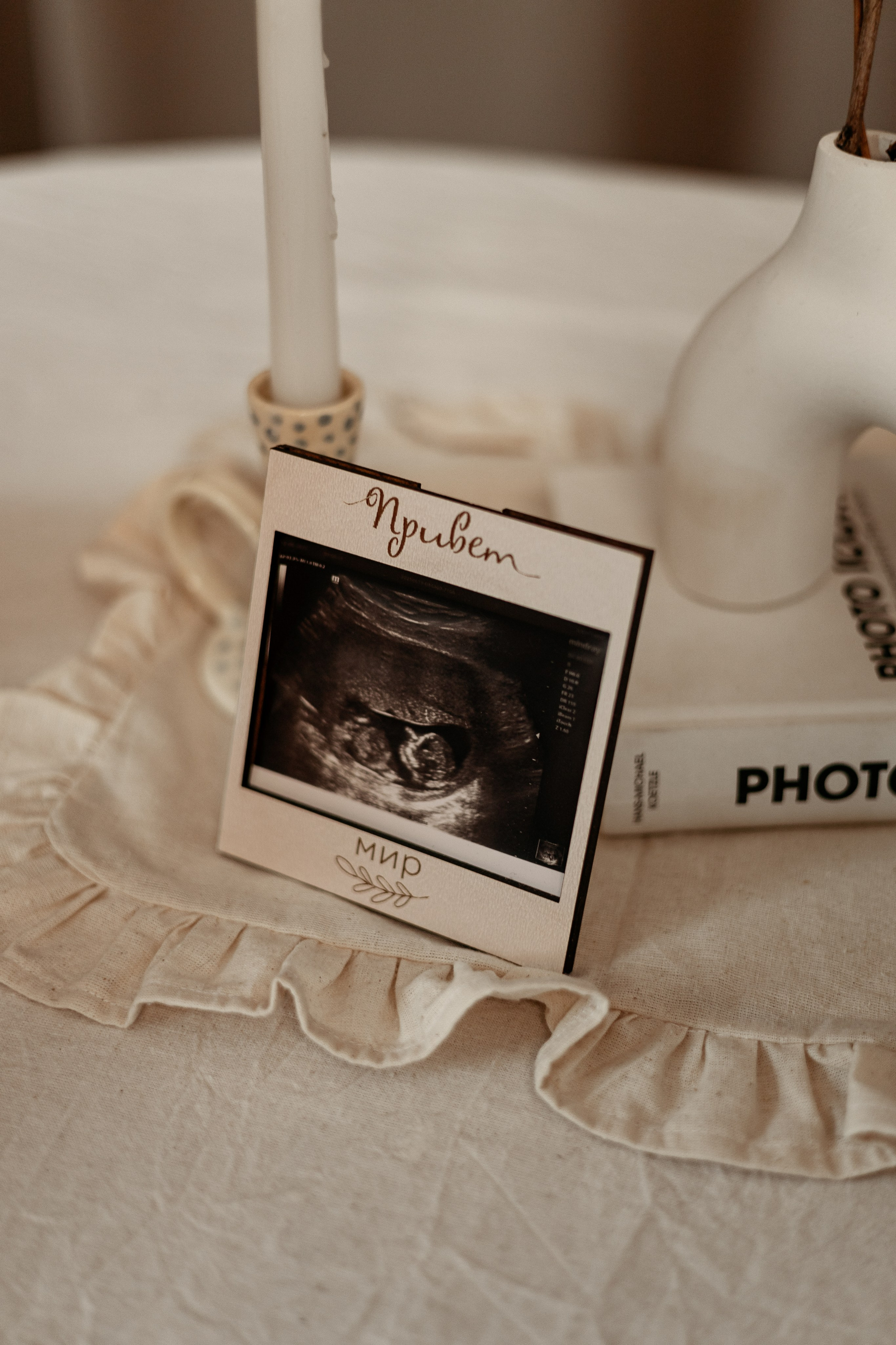 Фото с УЗИ-снимком: будущая мама прижимает к своему животу черно-белое УЗИ, улыбаясь сквозь слезы счастья.