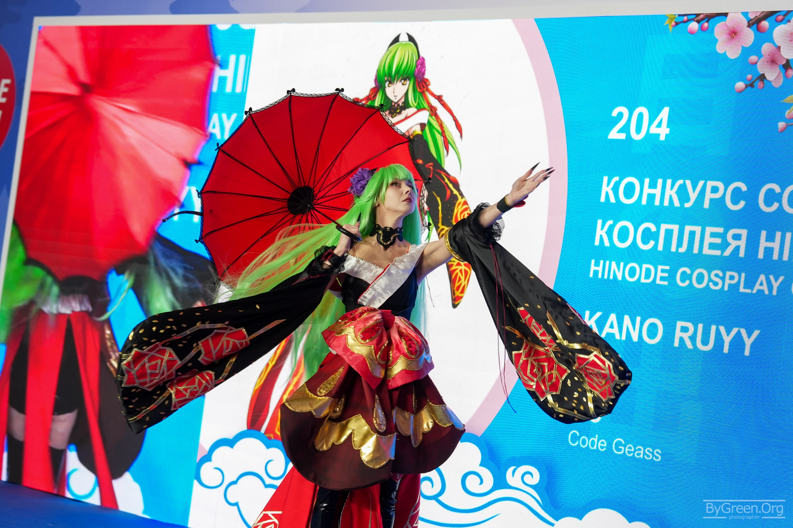 Cosplay of C.C. from Code Geass — red umbrella before the screen, Hinode 2026, Moscow