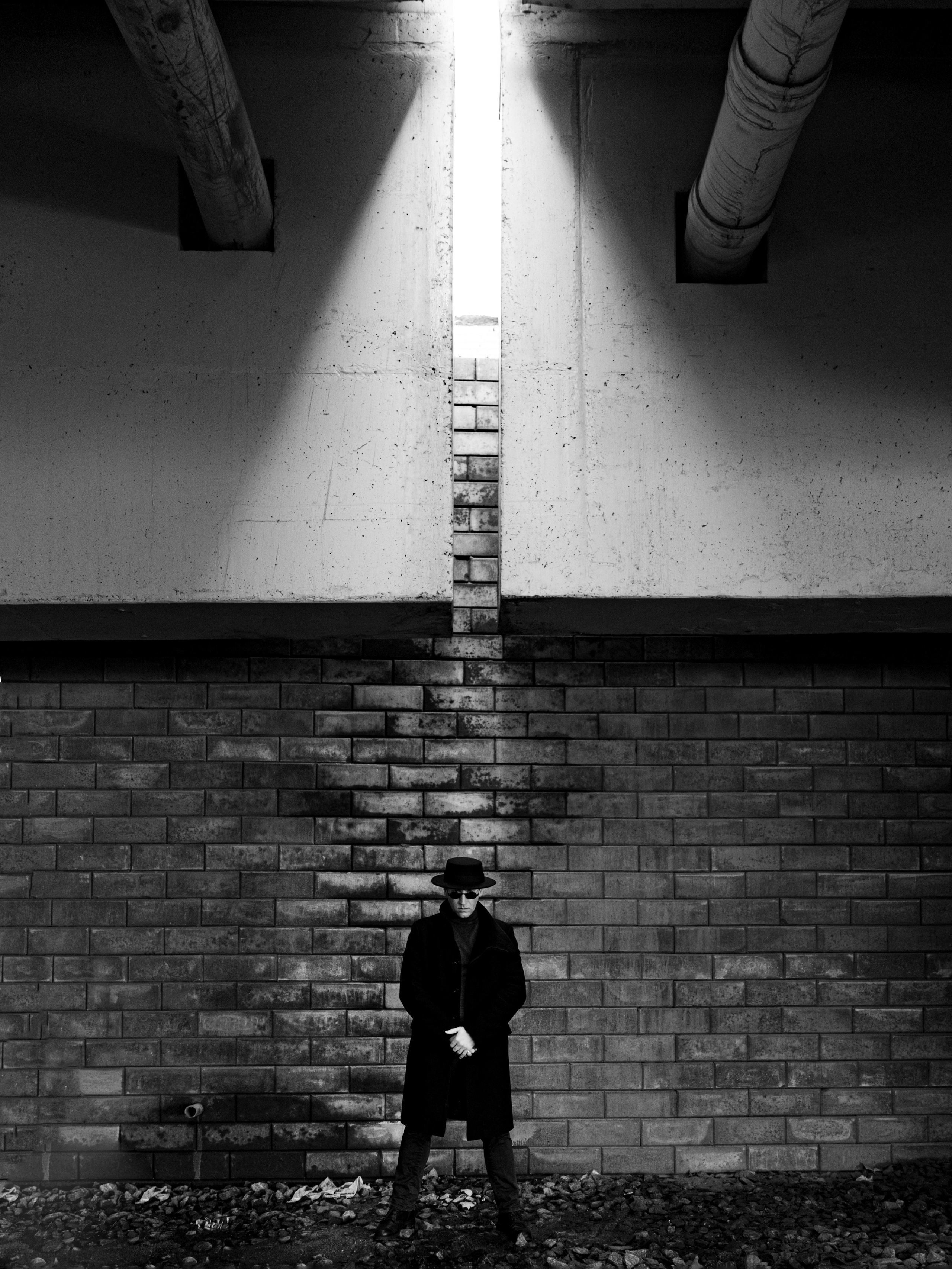 Черно-белый портрет мужчины у кирпичной стены