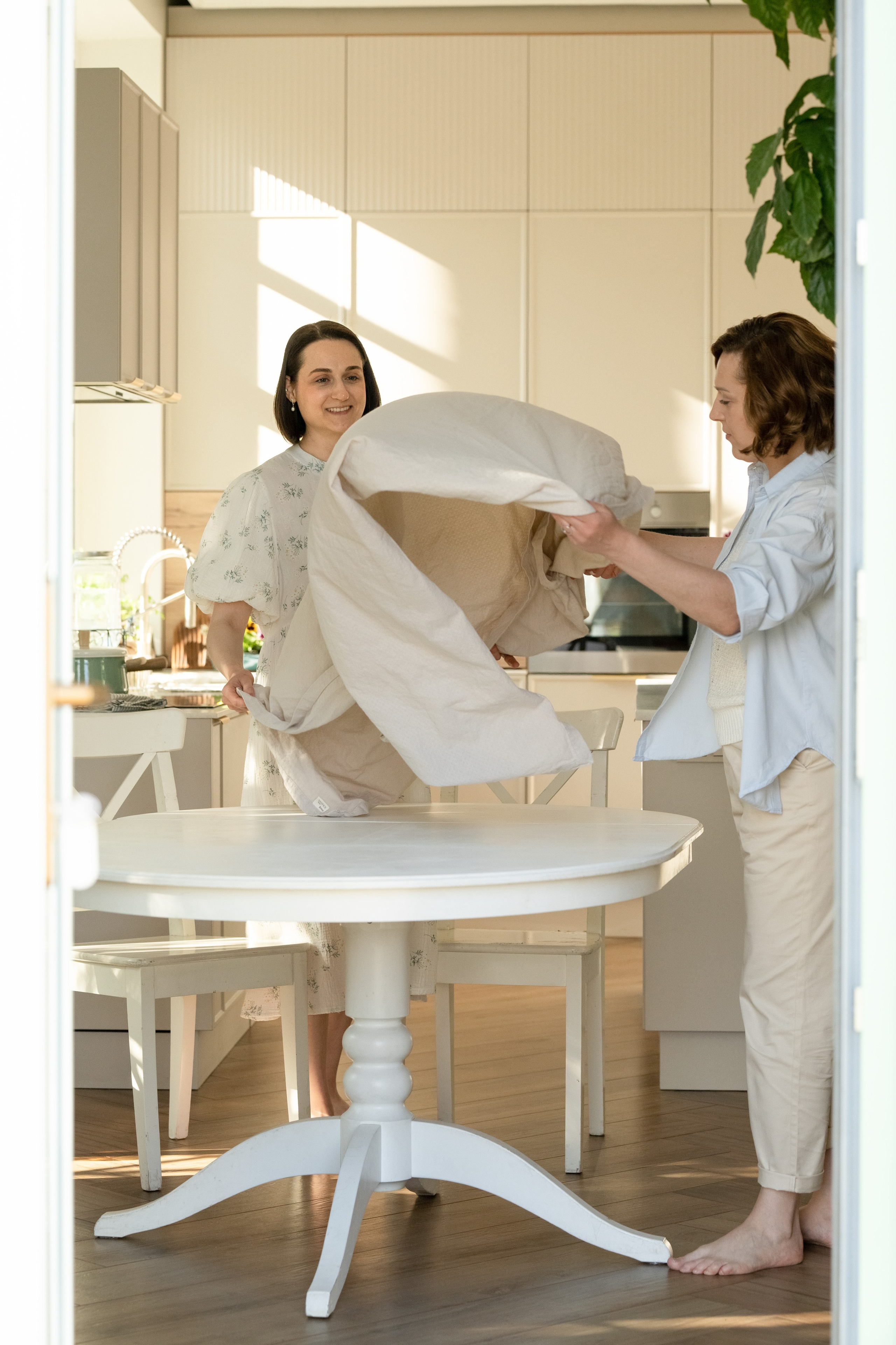 Две женщины накрывают на стол. Скатерть подбрасывают.