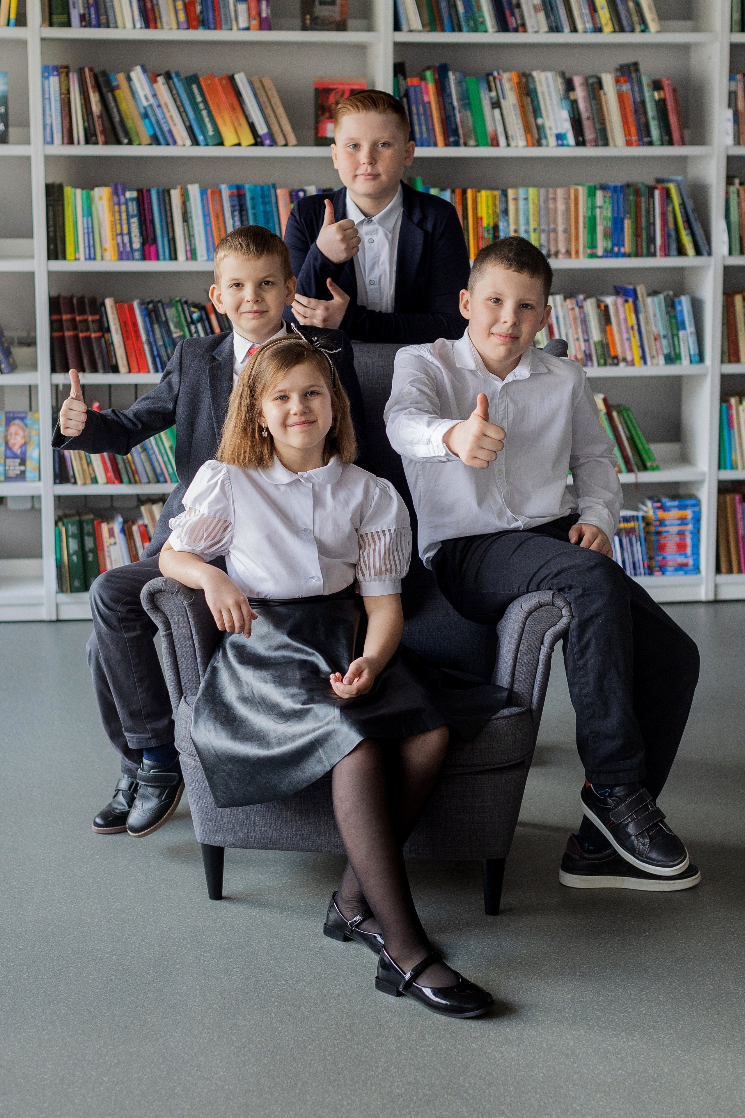 Три мальчика и девочка фотографируются в библиотеке