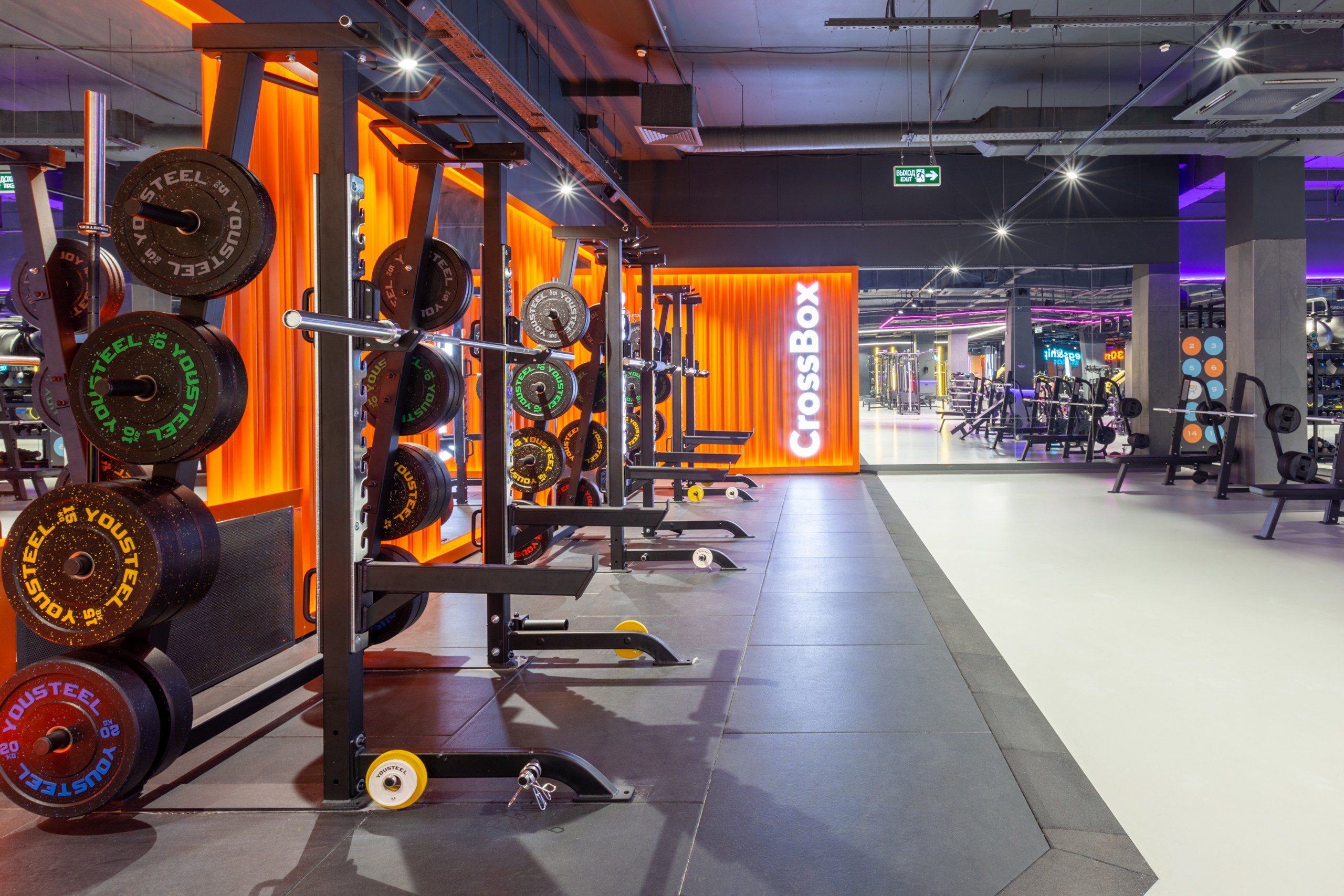 Оранжевая зона со штангами, в стиле промышленного контейнера. Большая неоновая надпись cross box в тренажёрном зале.