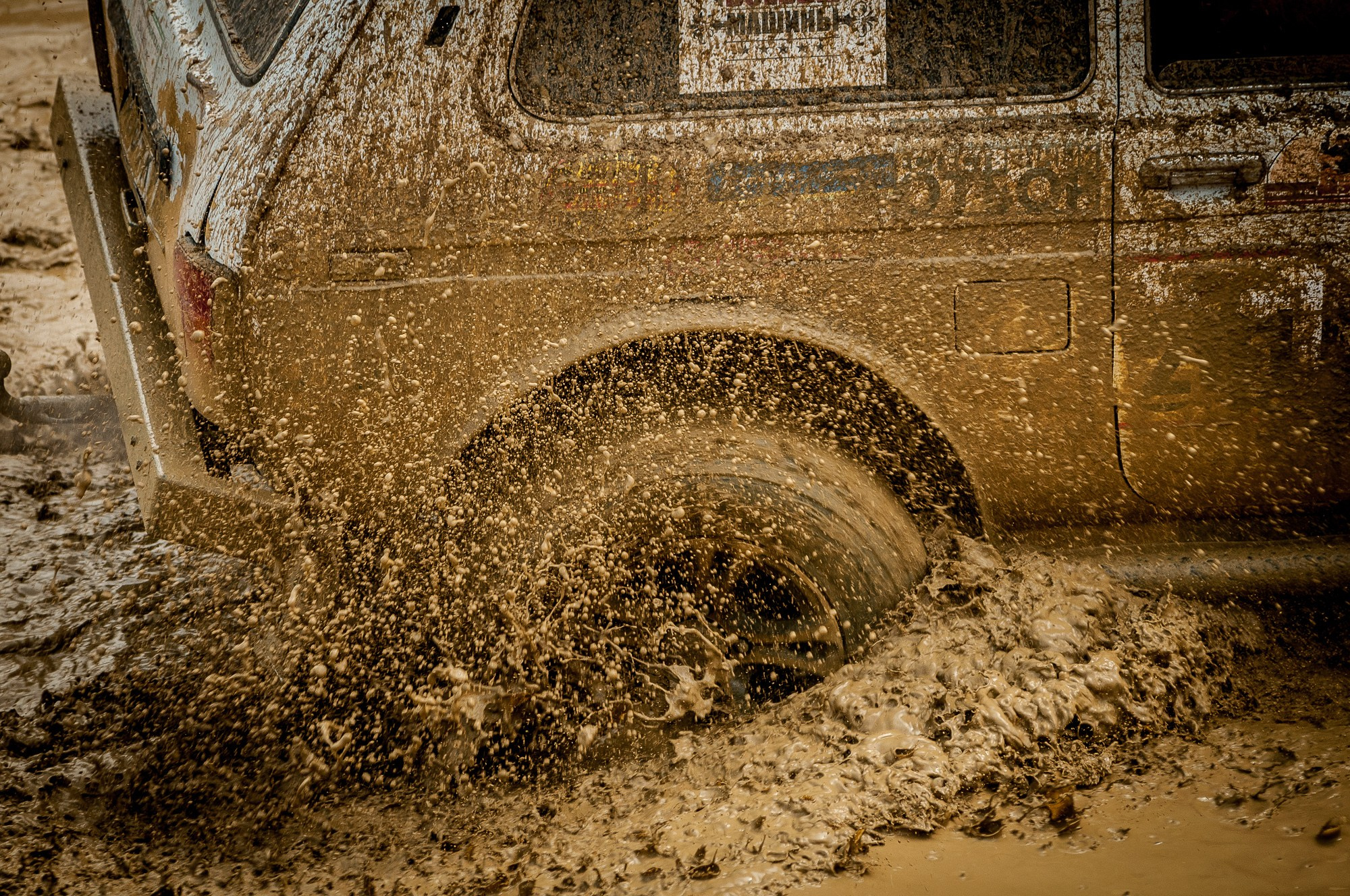 Грязь вырывается из-под колеса застрявшего автомобиля