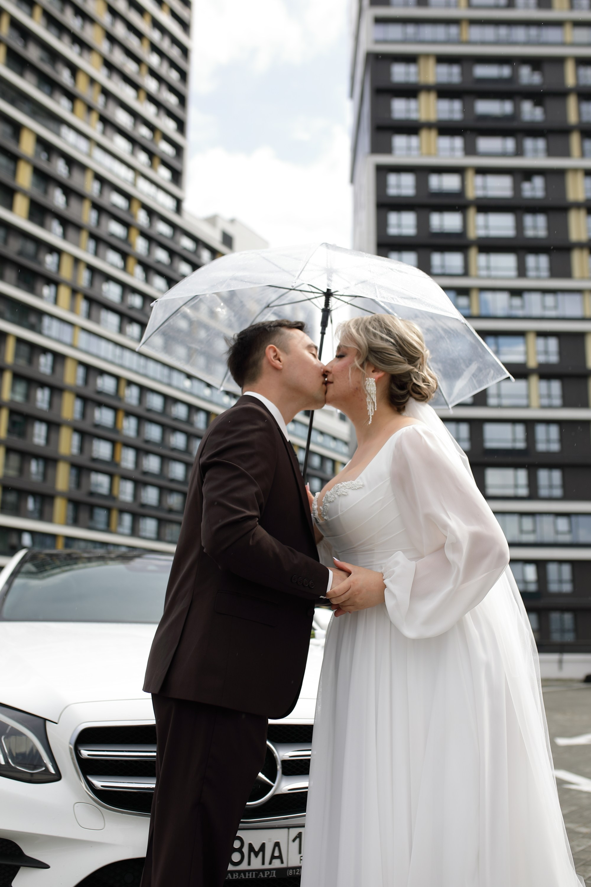 жених и невеста целуются под зонтом