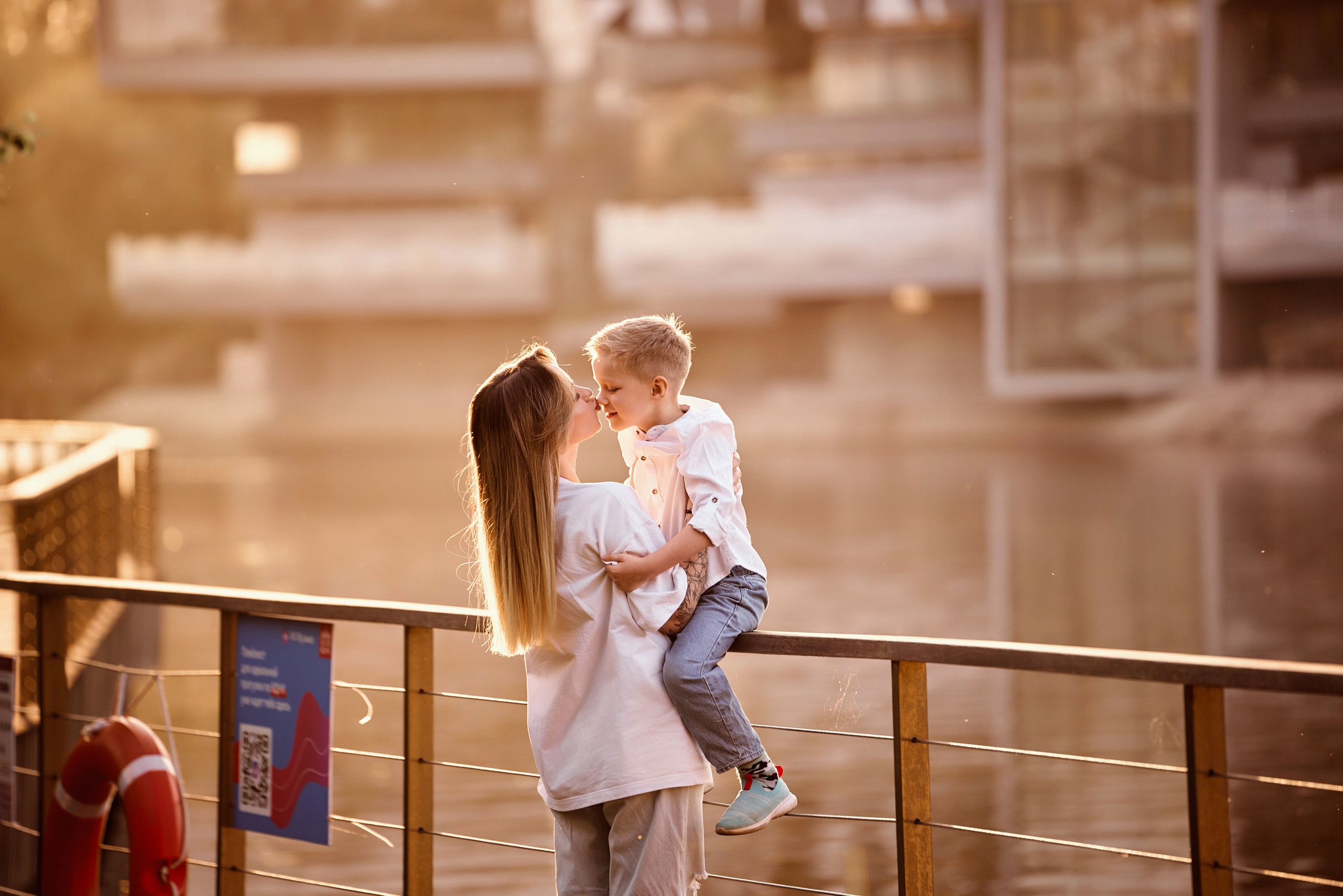 мама посадила сына на пирила ограждения пруда на ВДНХ, сзади зеркало воды пруда