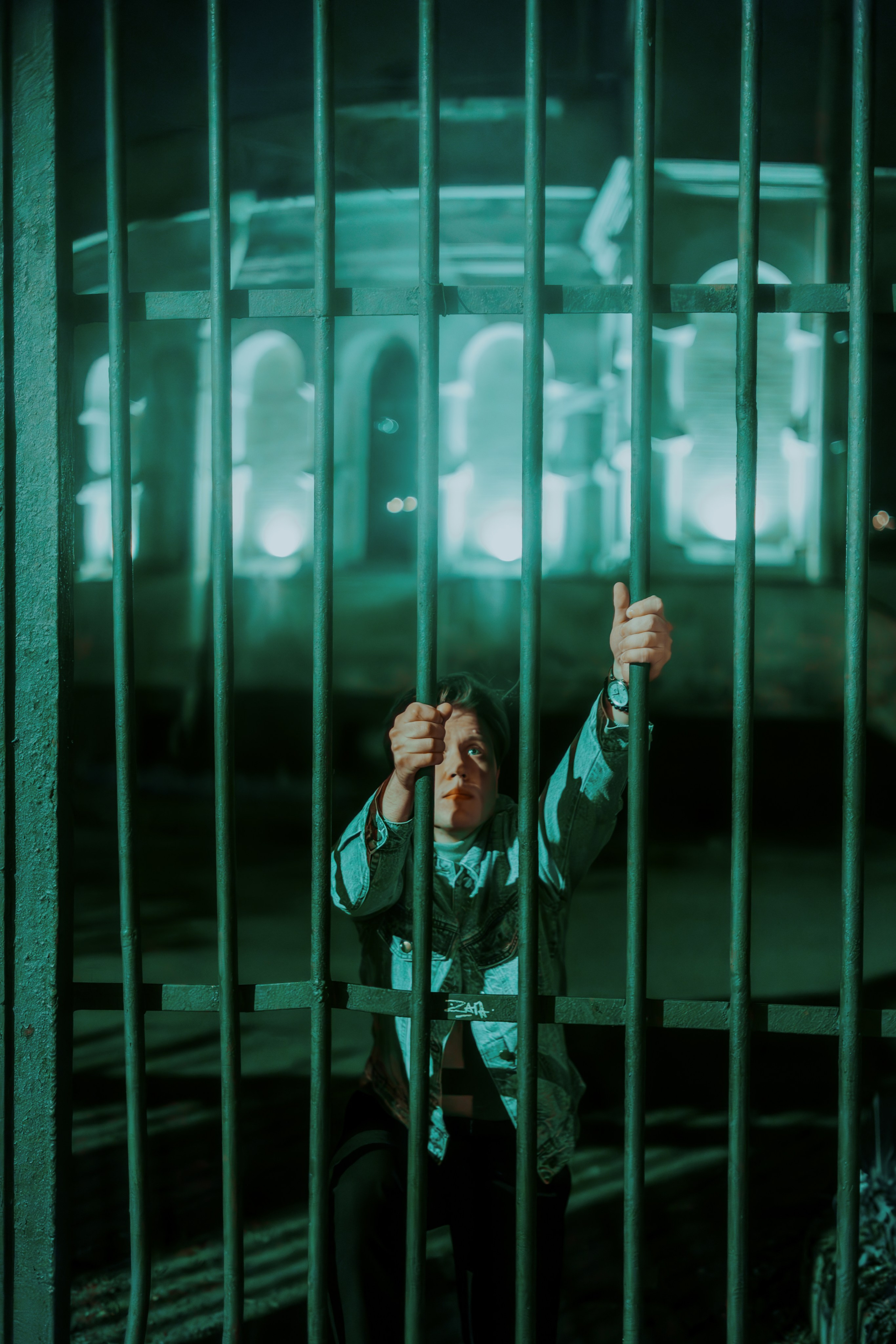 Молодой человек пытается перелезть через ограду