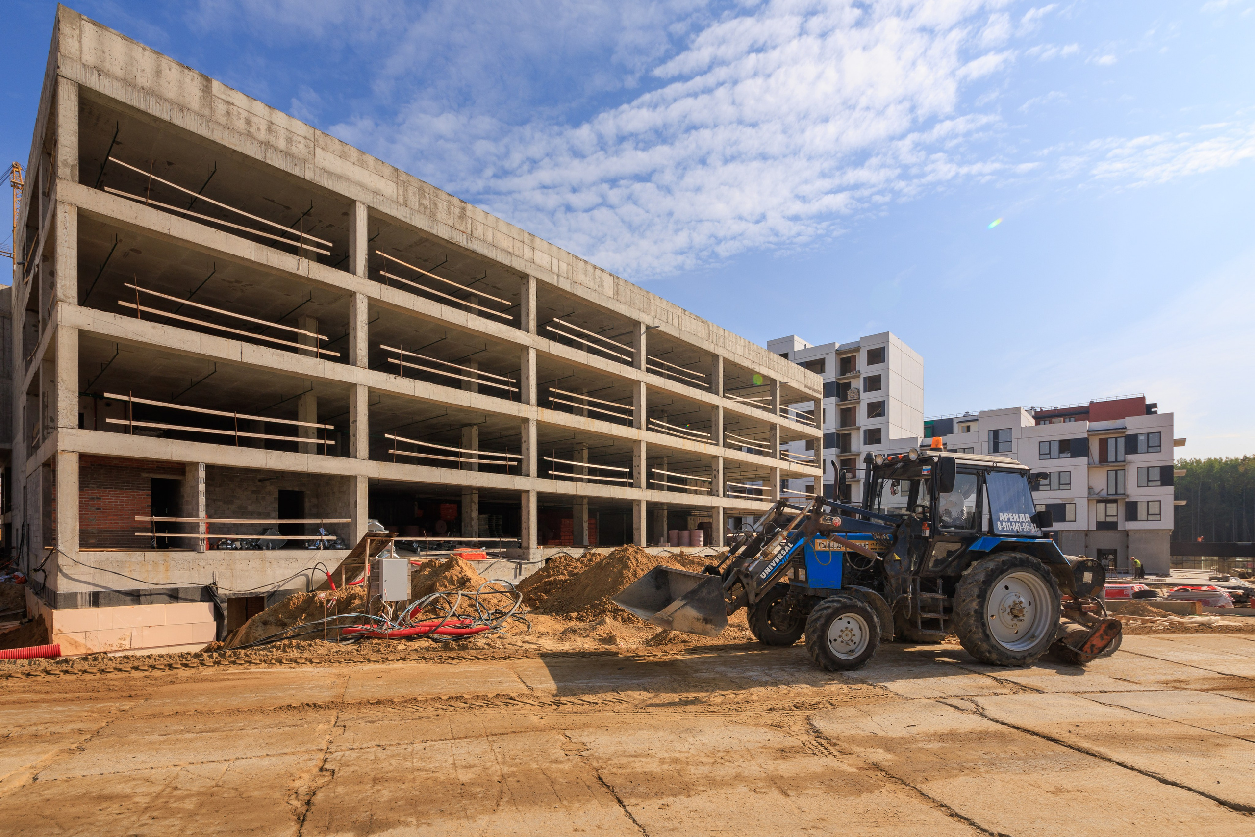 Мы видим большой бульдозер, который перемещает грунт, формируя основу для будущего строительства.