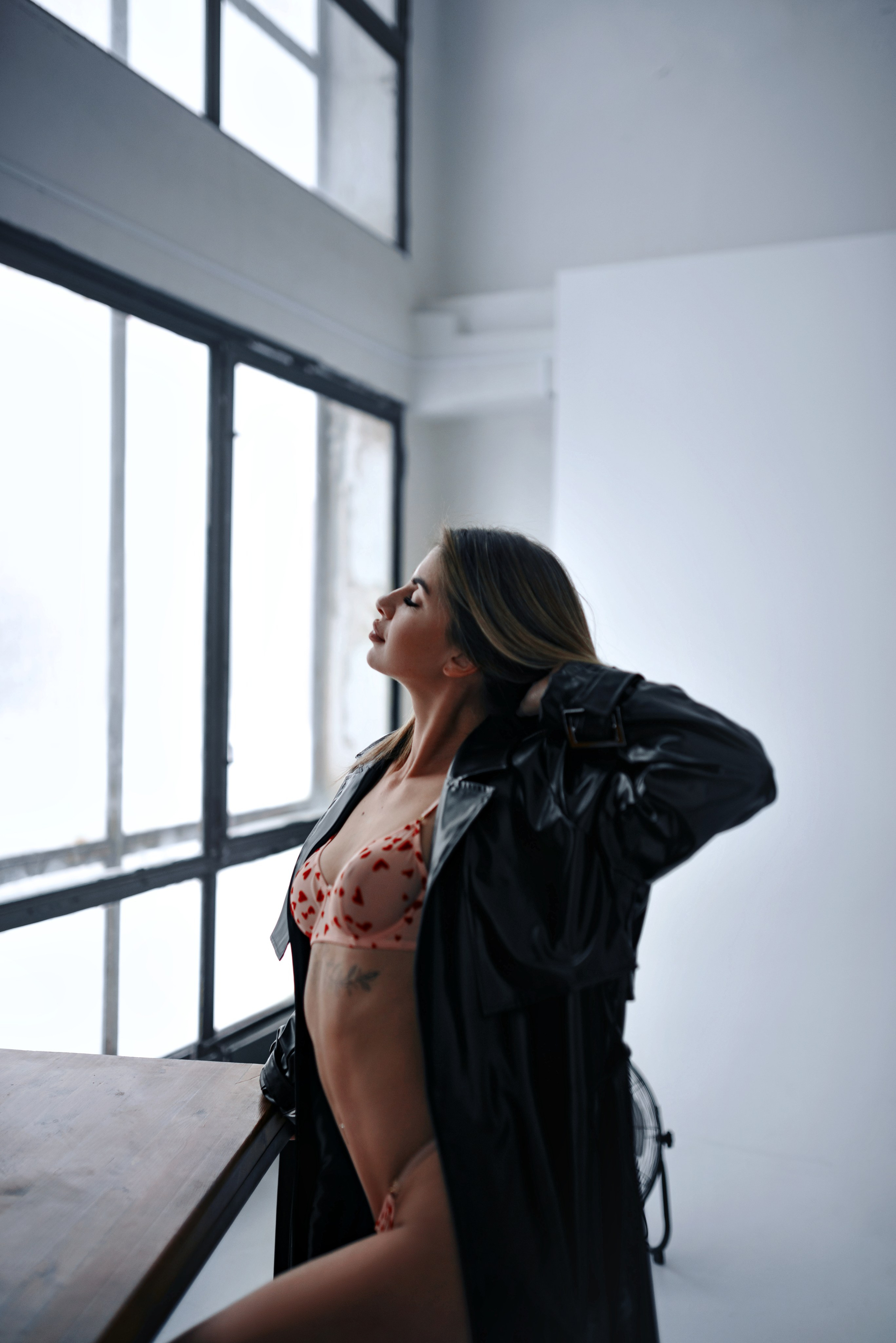 Творческая студийная съёмка девушки в кружевном белье и в кожаном плаще