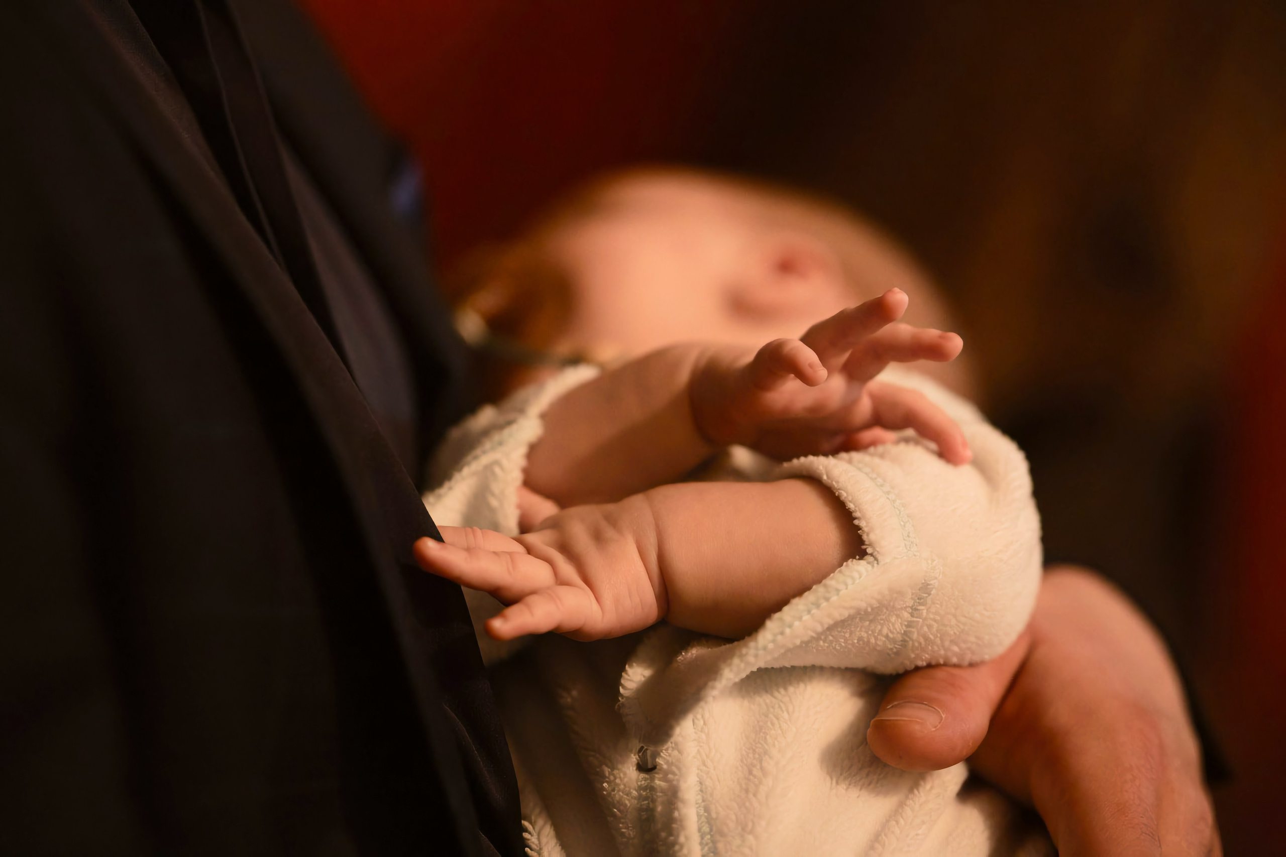 Руки новорождённого на руках священника, тёплый рассеянный свет храма — Екатеринбург, Илья Антропов