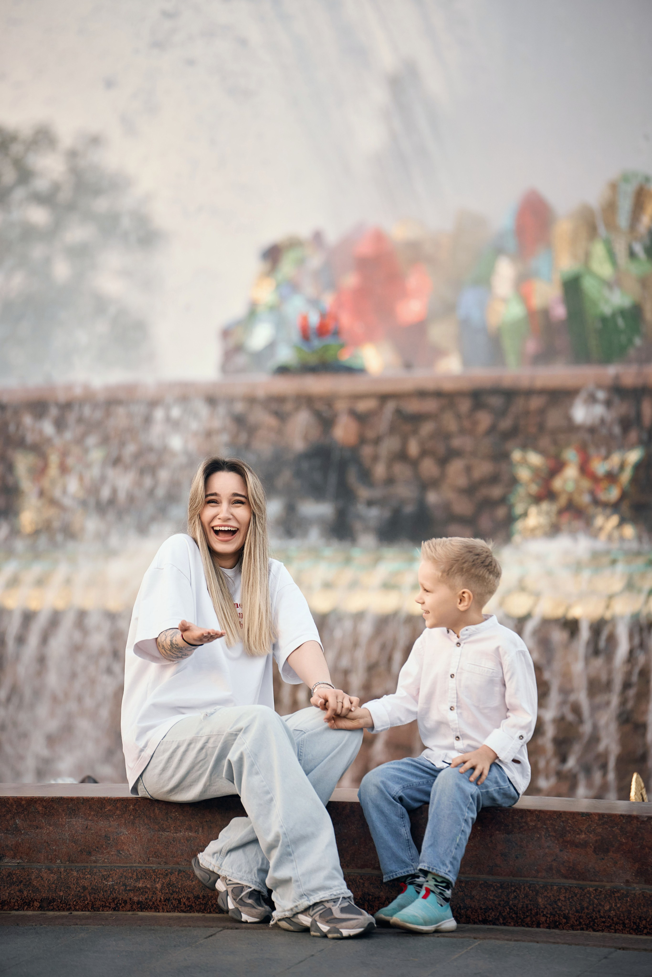 девушка и мальчик одетые в белые рубашки и голубые джинсы сидят у фонтана каменный цветок на ВДНХ 